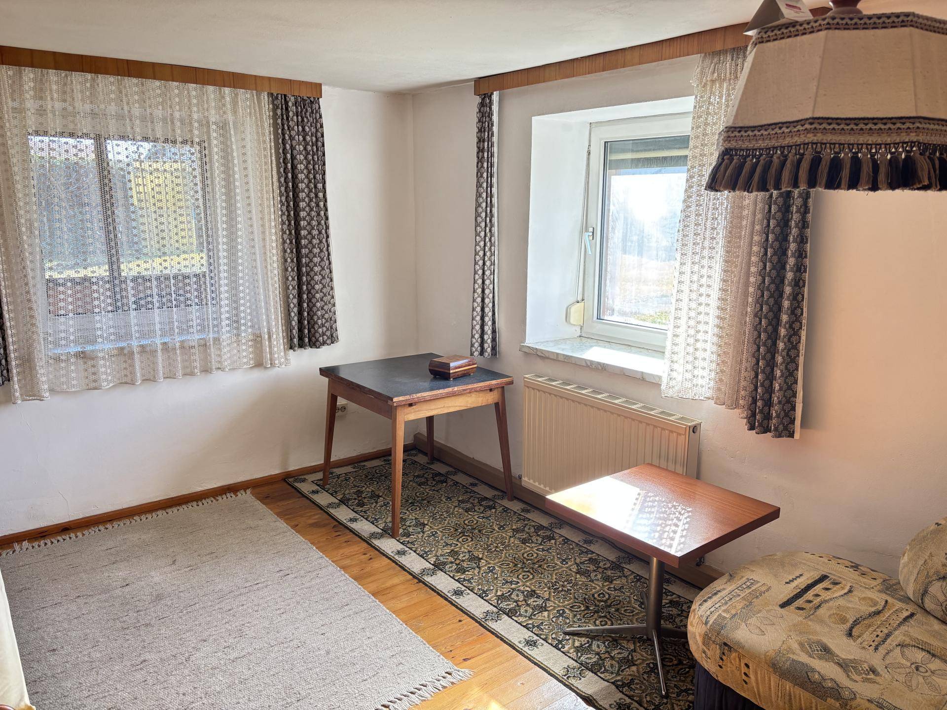 Helles Wohnzimmer mit zwei Fenstern, Teppich und traditioneller Einrichtung.