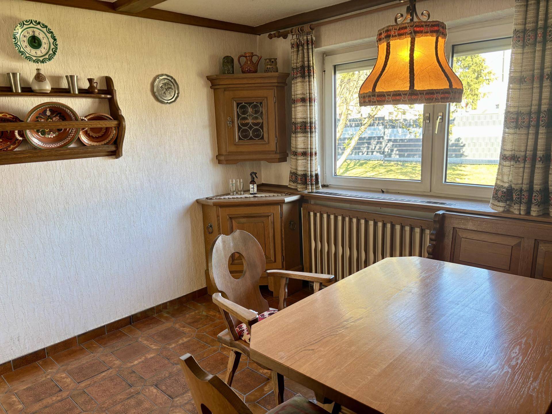 Gemütlicher Essbereich mit Holztisch, Eckschrank und Blick in den Garten.