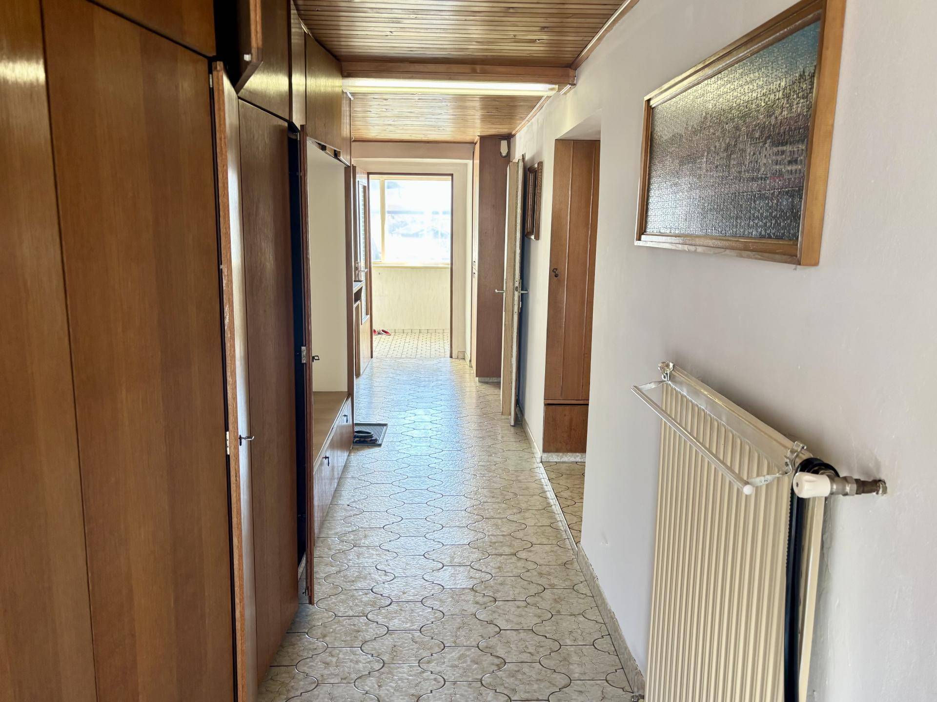 Langer Flur mit Holzvertäfelung an der Decke und Einbauschränken.
