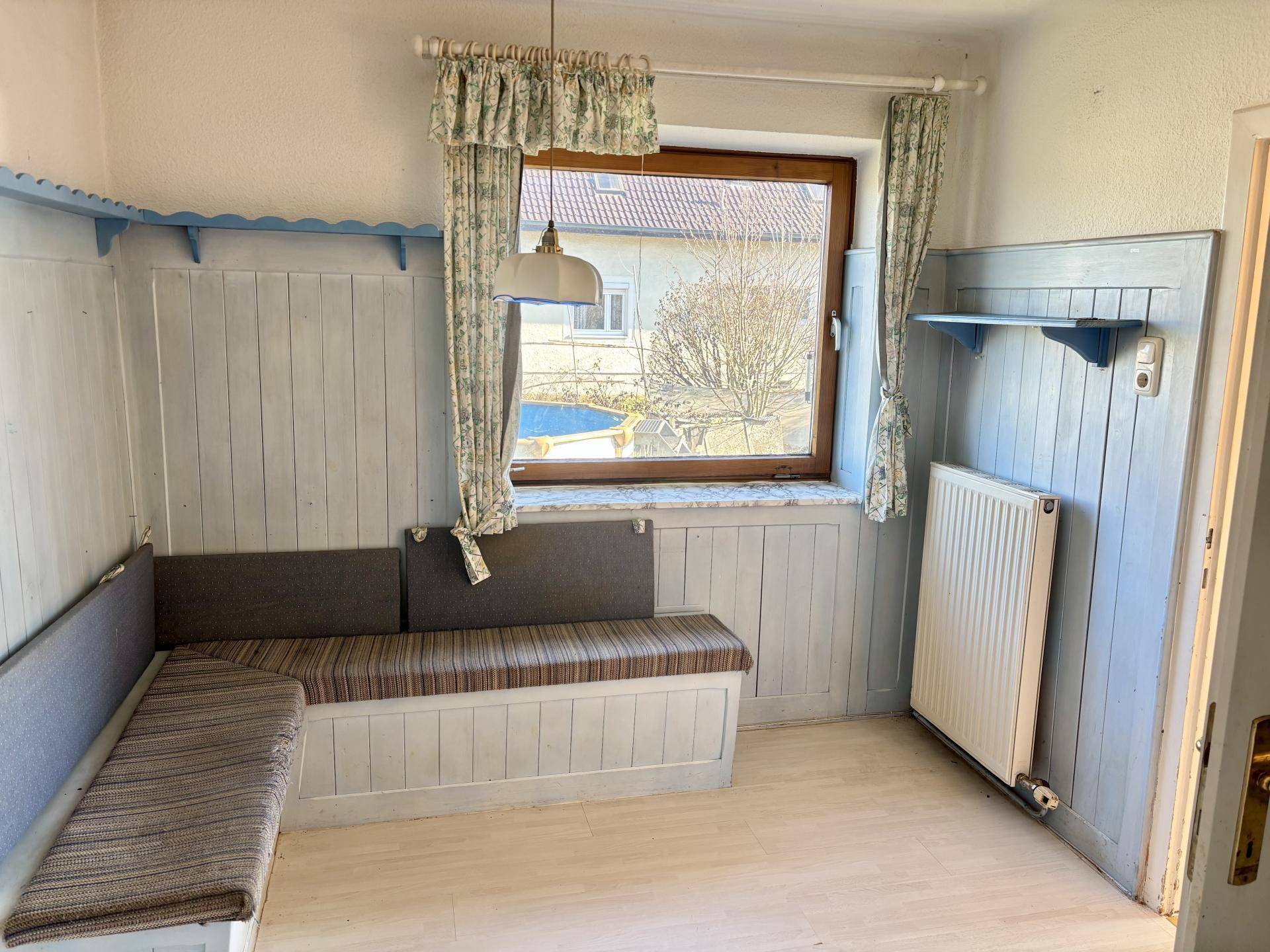 Gemütlicher Essbereich mit hellblauer Holzvertäfelung, eingebauter Sitzbank und Fenster.
