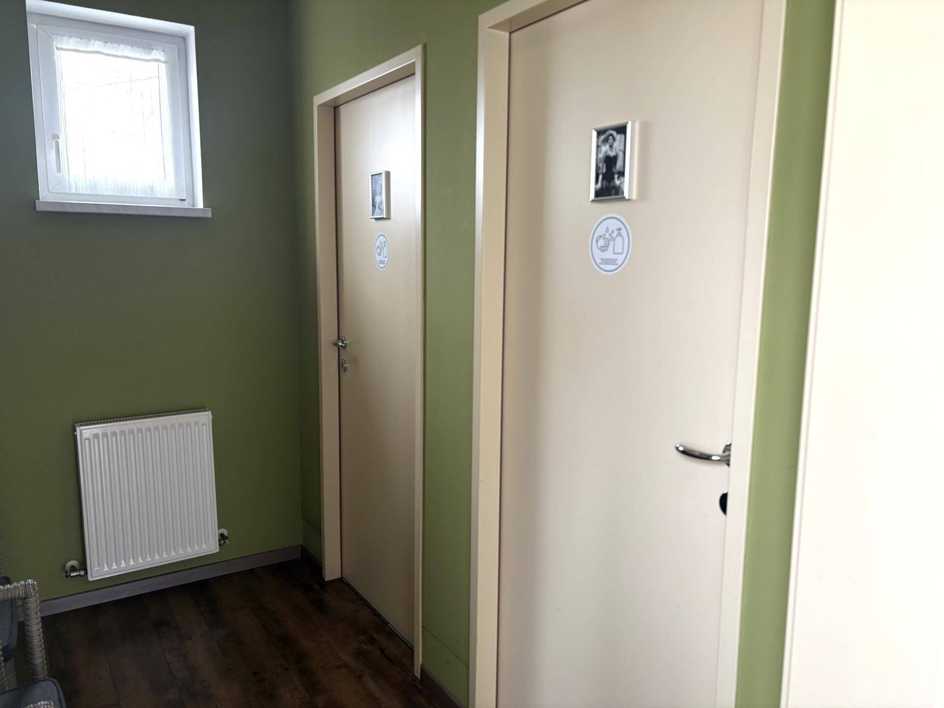 Heller Flur mit zwei Türen, die wahrscheinlich zu Toiletten führen, und einem Fenster.