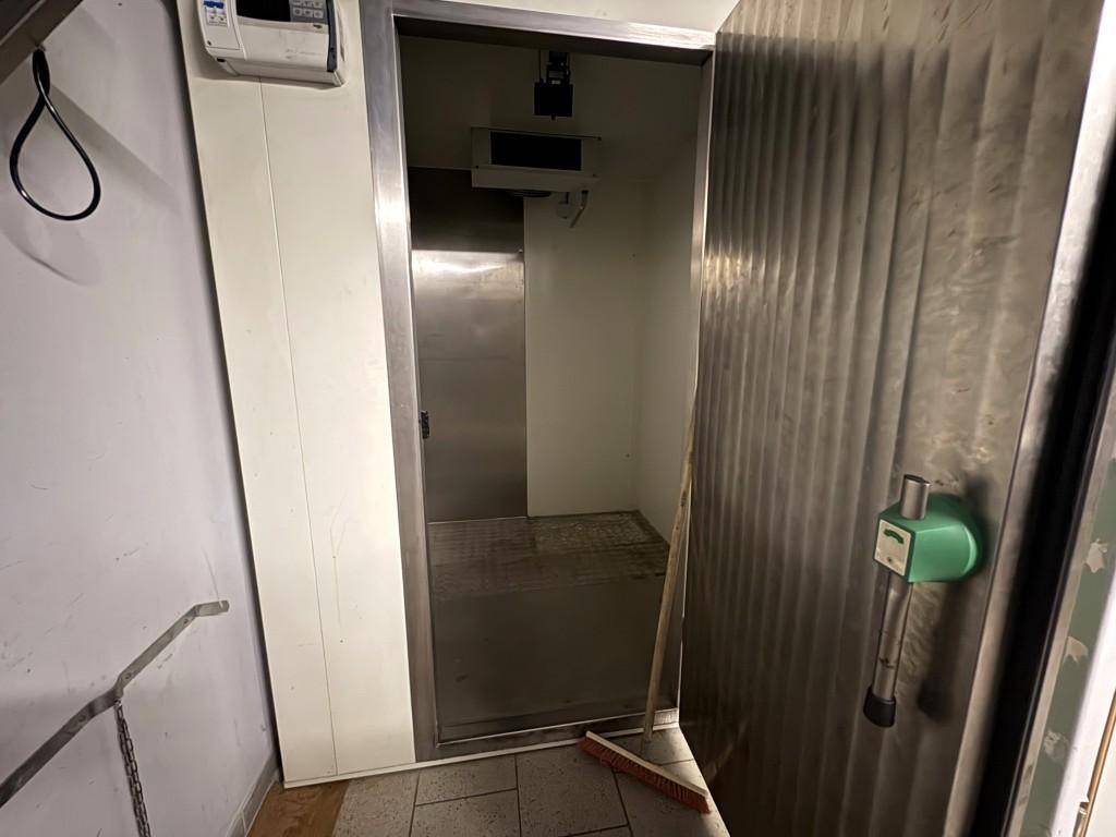 Innenansicht eines begehbaren Kühlraums mit Metallwänden und einem Gitterrostboden.