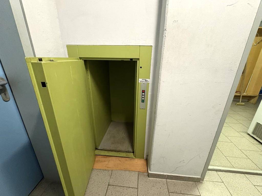 Technikraum mit einem kleinen Lastenaufzug und gefliestem Boden.