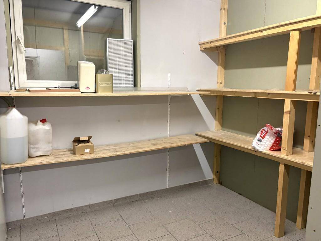 Lagerraum mit Holzregalen, gefliestem Boden und einem Fenster für natürliche Belüftung.