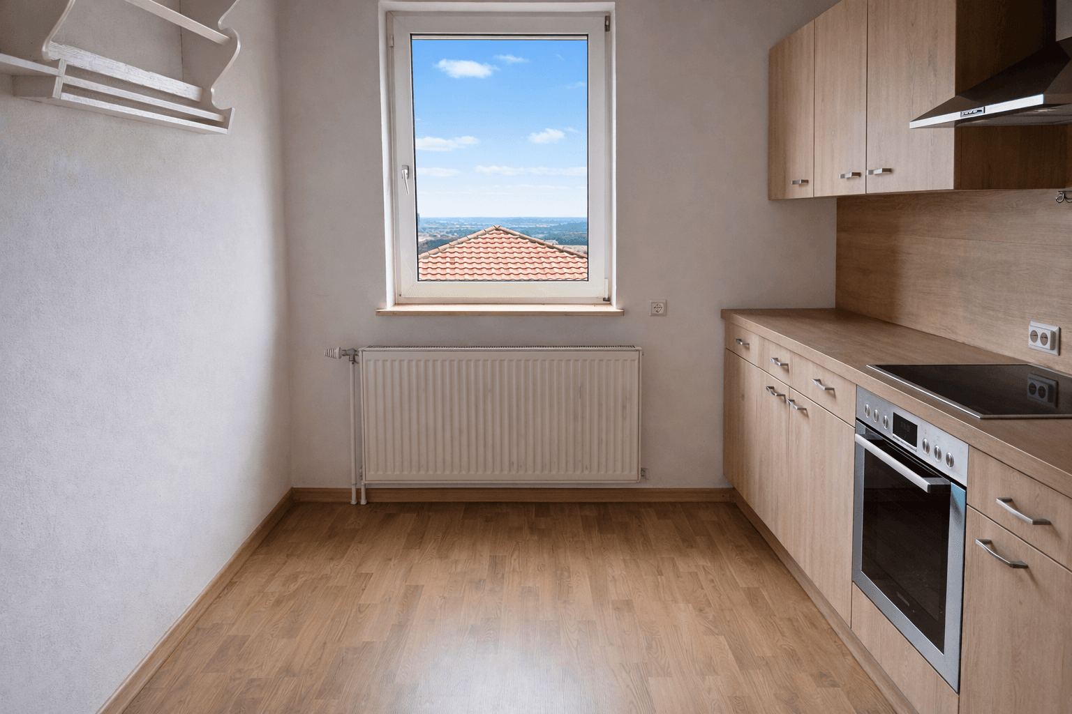 Helle Küche mit Holzoptik-Einbaumöbeln, Laminatboden und Fenster mit Fernblick.