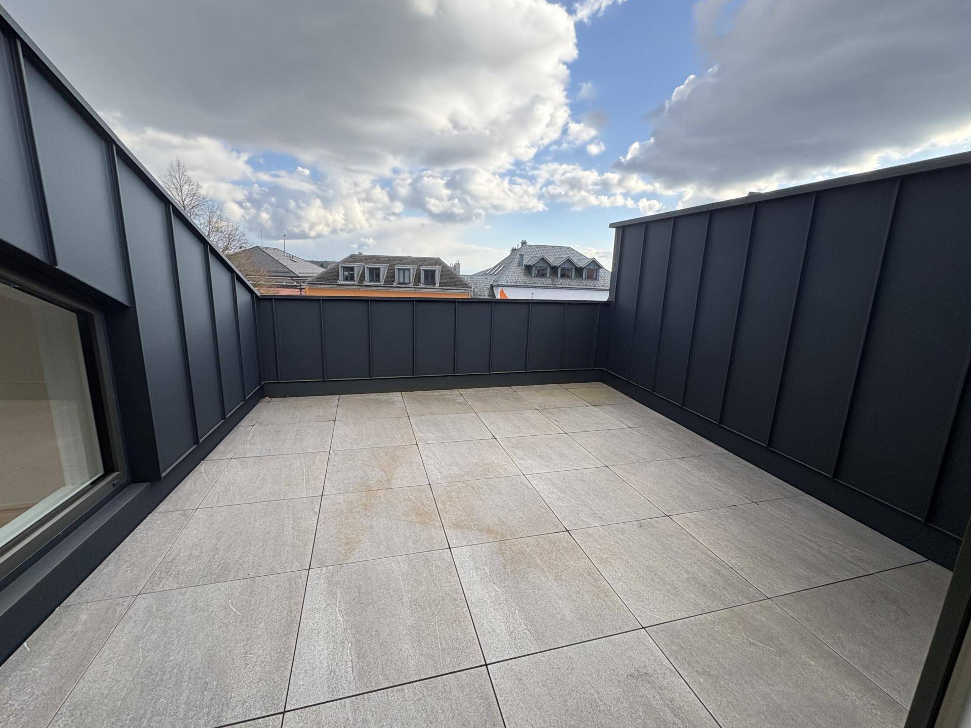 Geräumige Dachterrasse mit modernen Fliesen und Blick auf die umliegenden Dächer.