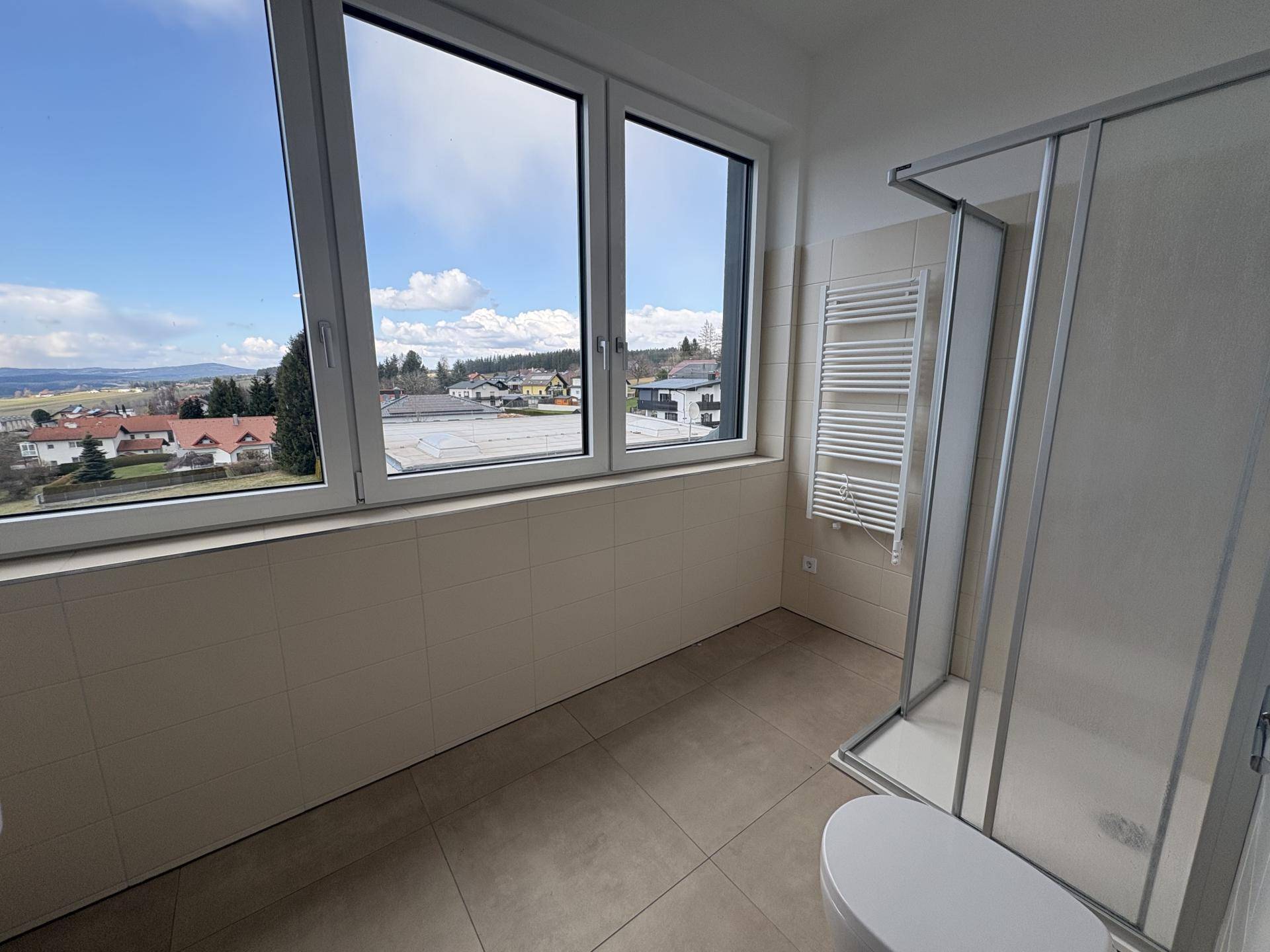 Modernes Badezimmer mit Dusche, beheiztem Handtuchhalter und großem Fenster mit Weitblick.