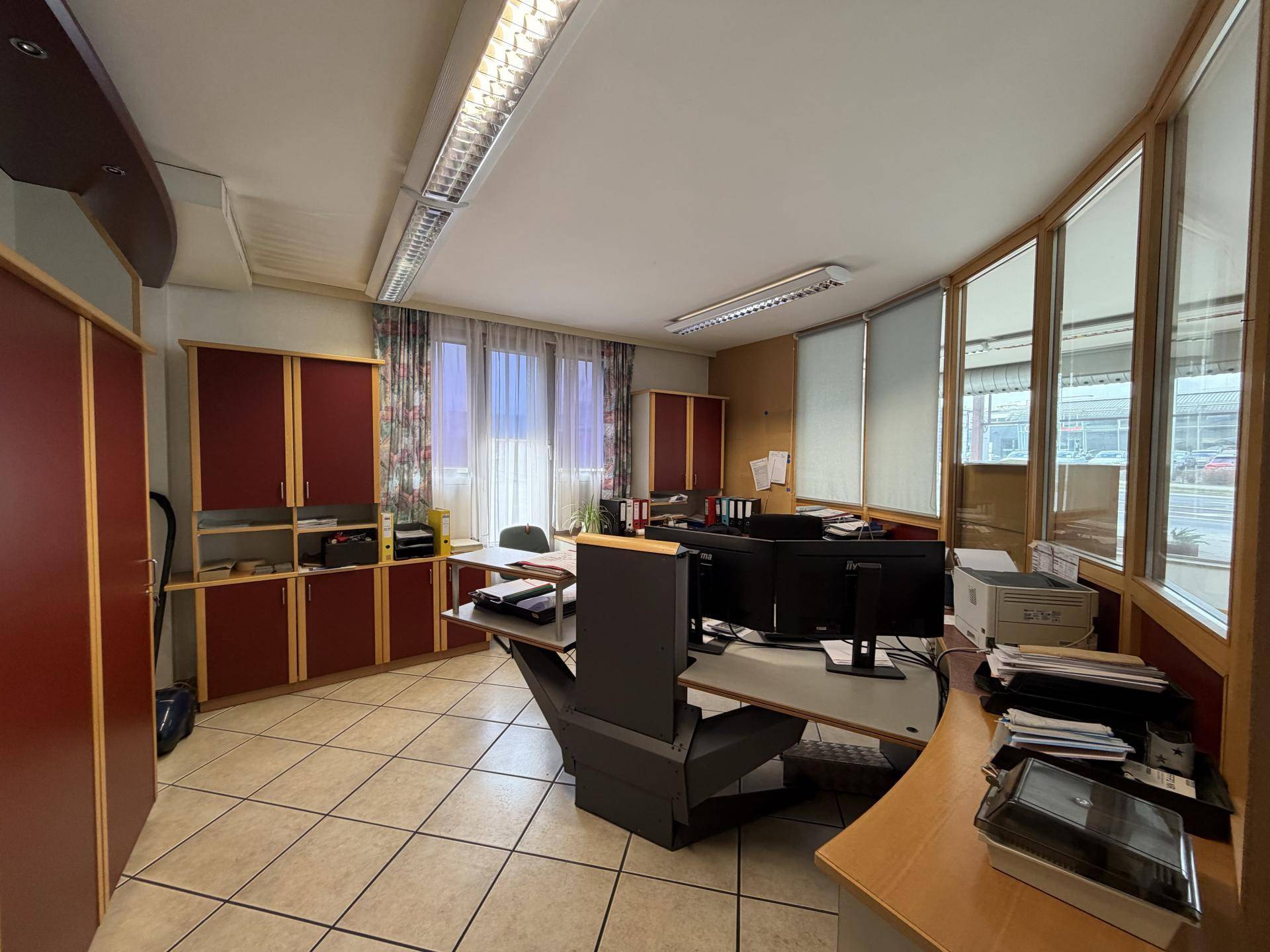 Modern eingerichtetes Büro mit mehreren Arbeitsplätzen, großen Fenstern und funktionalen Möbeln.