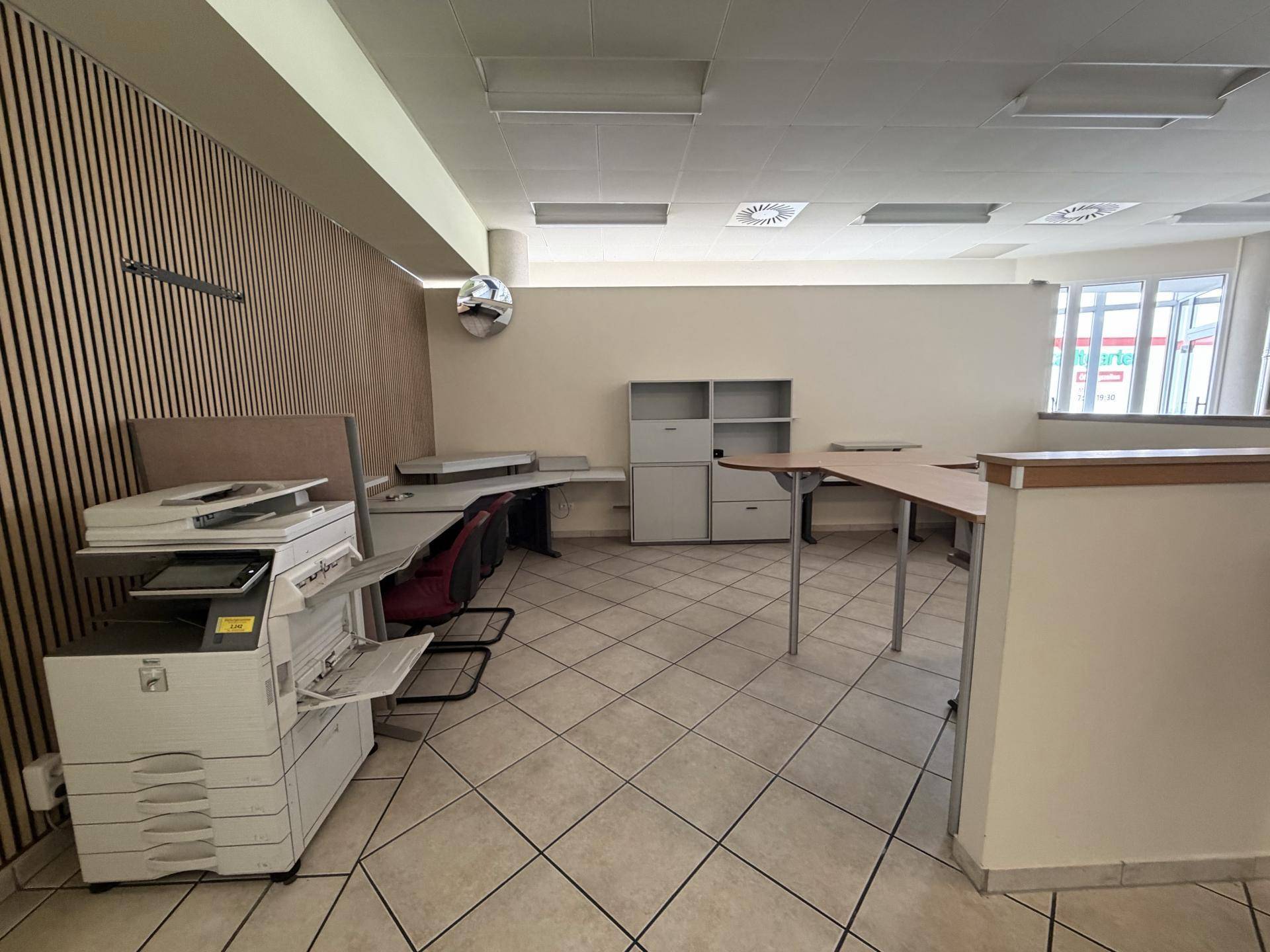 Geräumiges Büro mit mehreren Schreibtischen, Kopierer und großen Fenstern, ideal für Teamarbeit.