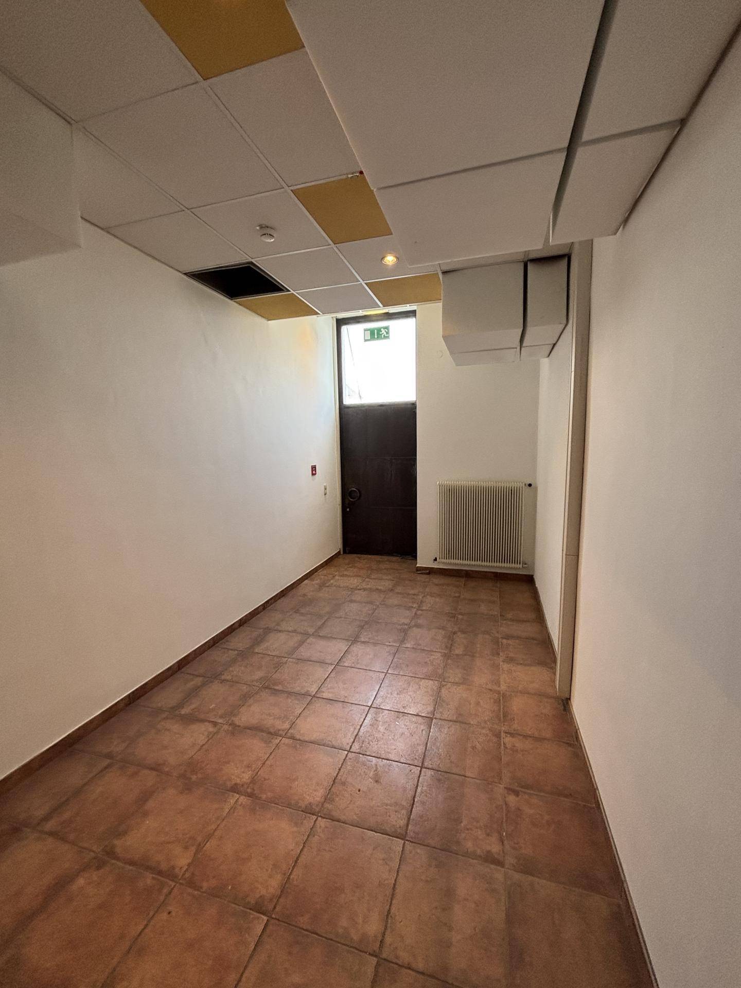 Kleiner Raum mit Terrakotta-Fliesenboden und einem Fenster, geeignet als Abstellraum oder Archiv.
