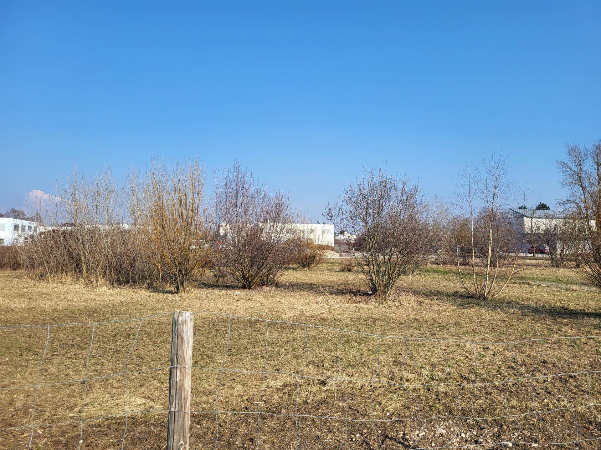 Weitläufiges unbebautes Grundstück mit spärlicher Vegetation unter einem weiten blauen Himmel.