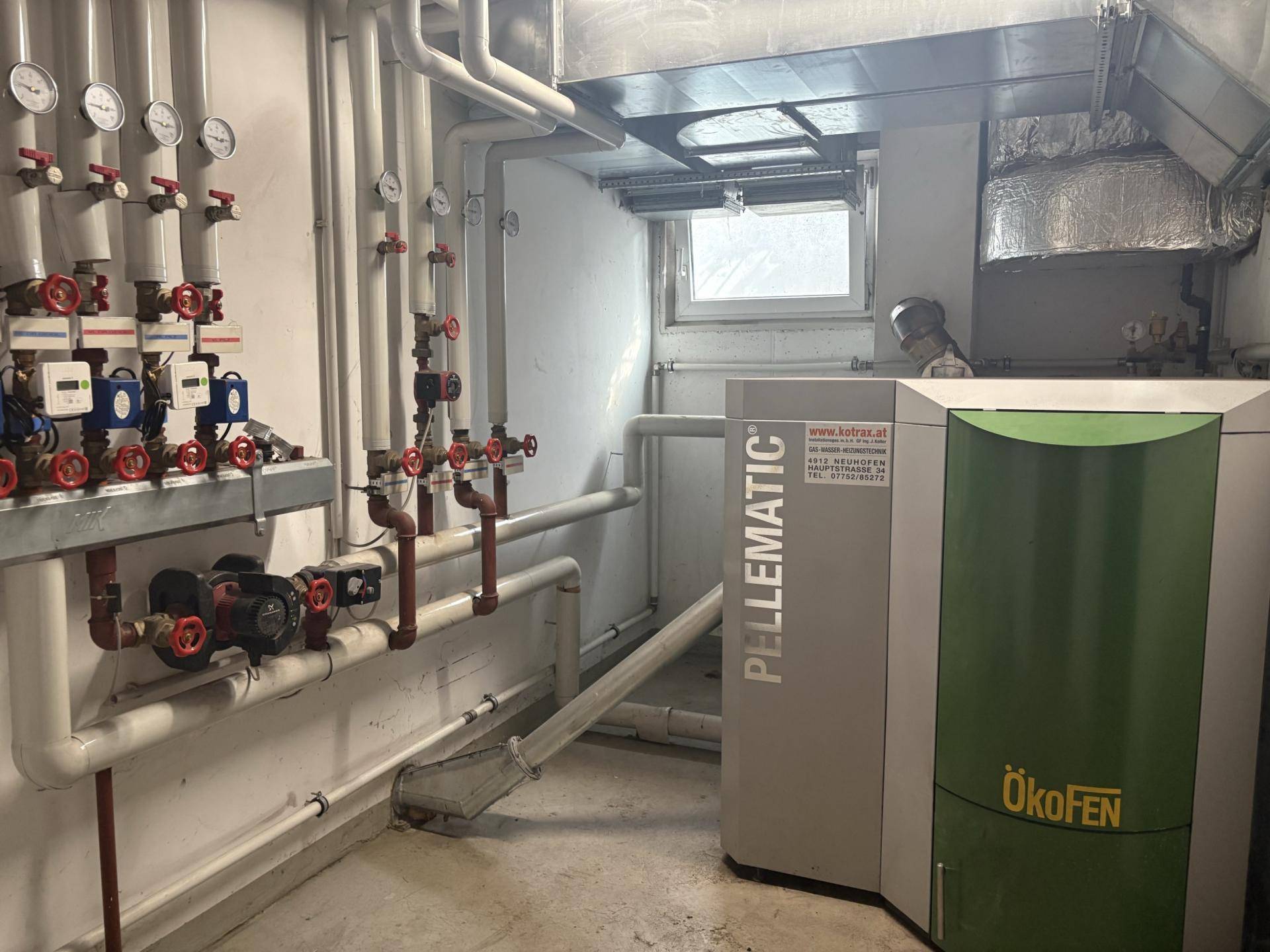 Heizungsraum mit moderner Pelletheizung und umfangreicher Rohrinstallation.