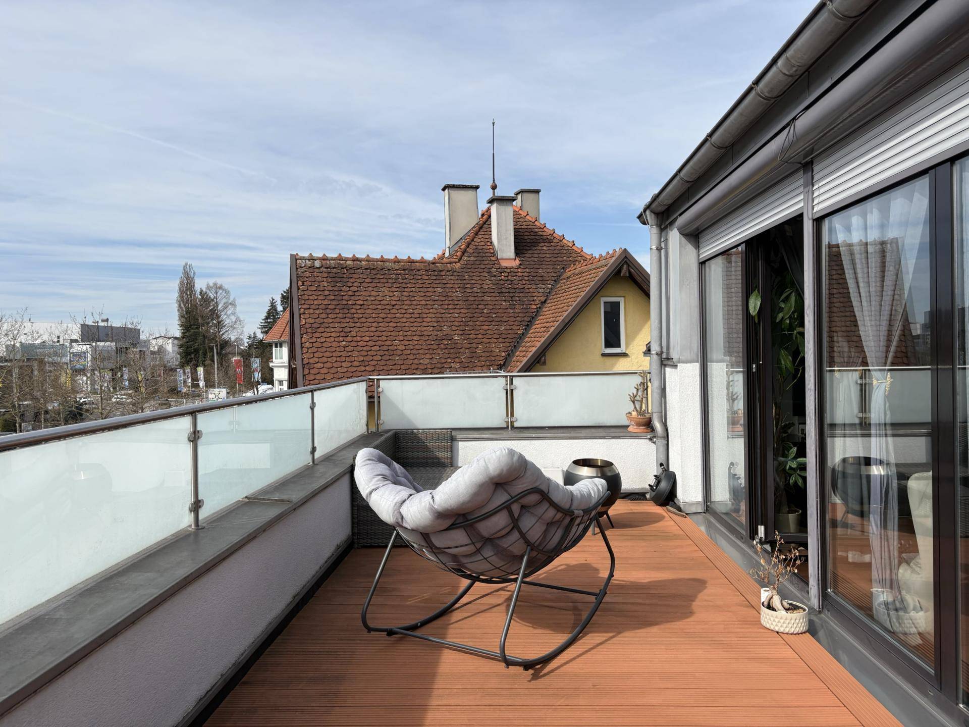 Sonniger Terrassenbereich mit bequemen Loungemöbeln und Blick auf die Dächer.