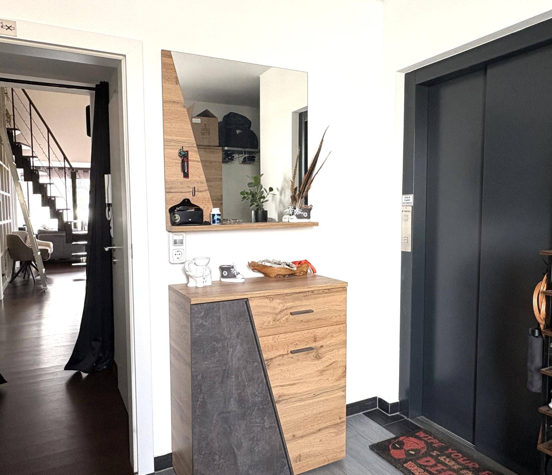 Moderner Flur mit Garderobe, Spiegel und Zugang zum Wohnbereich.