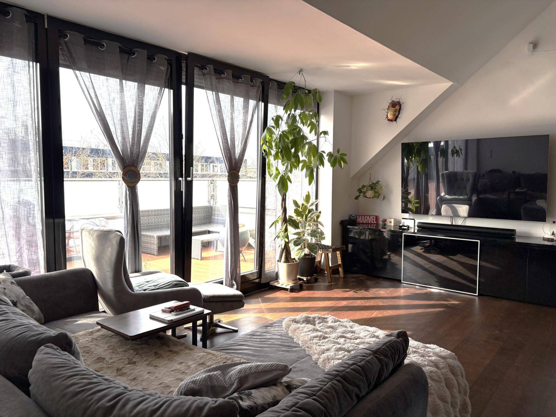 Helles Wohnzimmer mit großen Fenstern, Zugang zur Terrasse und gemütlicher Sitzecke.