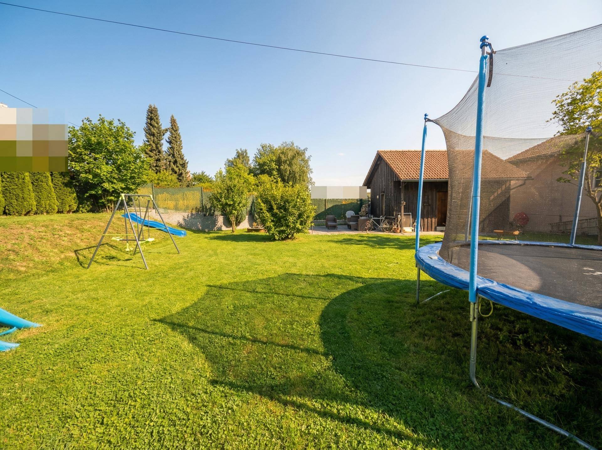 Großer Garten mit Trampolin, Schaukel und viel Grünfläche für Kinder.