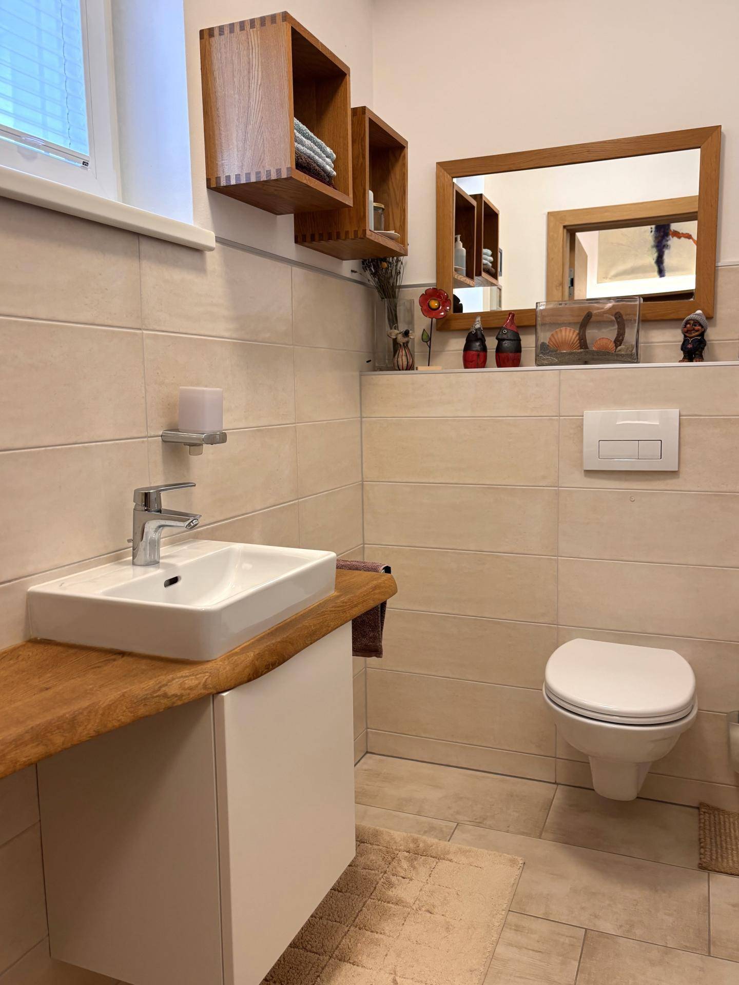 Modernes Gäste-WC mit wandhängendem WC, Einzelwaschbecken und Holzablage.