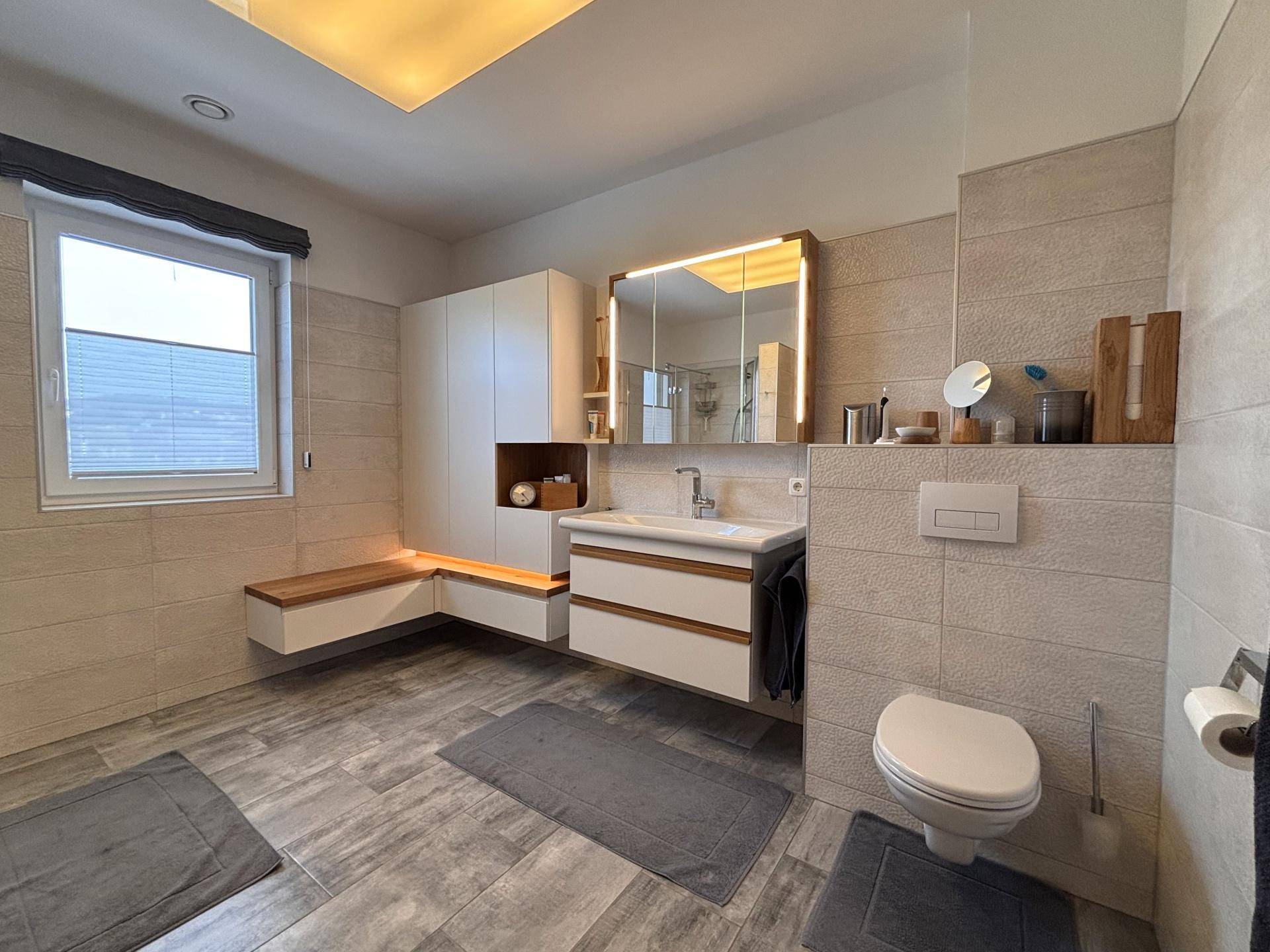 Modernes Badezimmer mit begehbarer Dusche, WC, großem Waschtisch und Fenster.