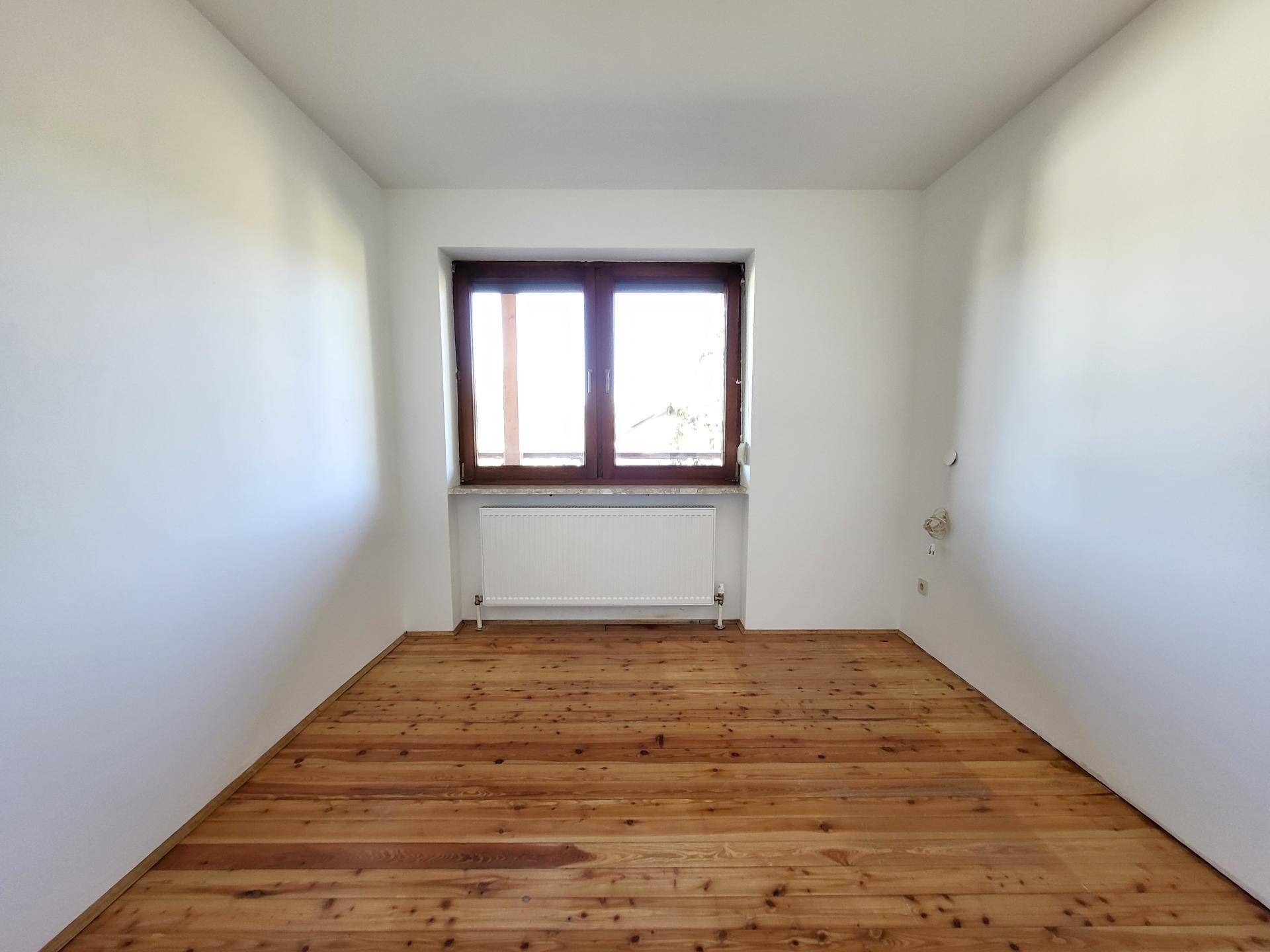 Helles Zimmer mit rustikalem Holzdielenboden und großem Fenster.