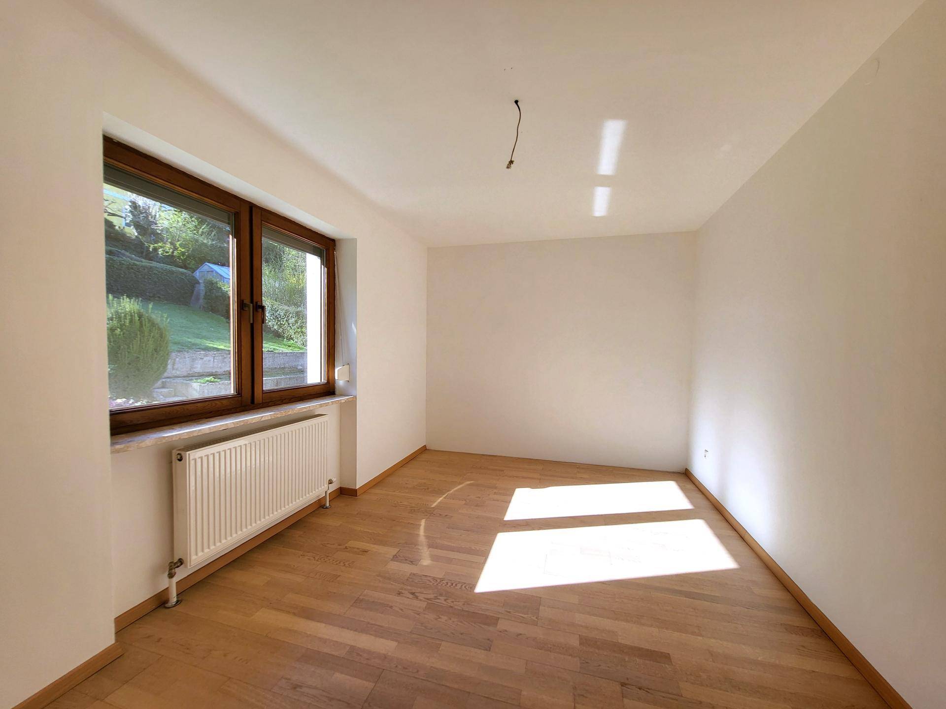 Sonniger Raum mit Parkettboden und Blick ins Grüne, ideal als Schlaf- oder Arbeitszimmer.