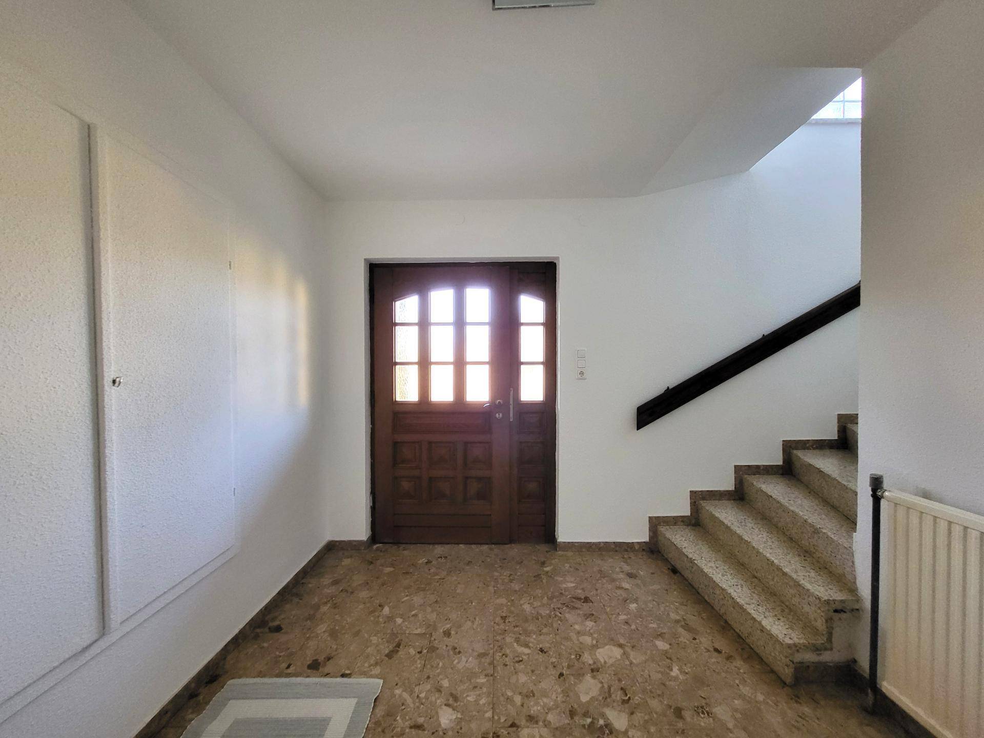 Eingangsbereich mit Steinfliesenboden und Treppe zum Obergeschoss.