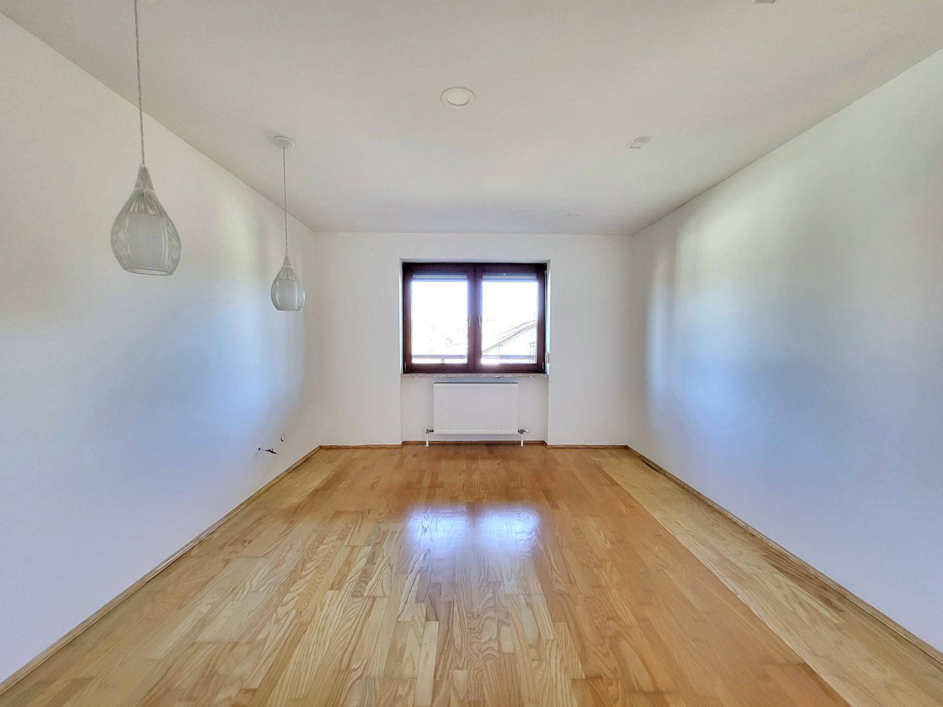 Leeres Zimmer mit Parkettboden und Fenster, bereit für individuelle Gestaltung.