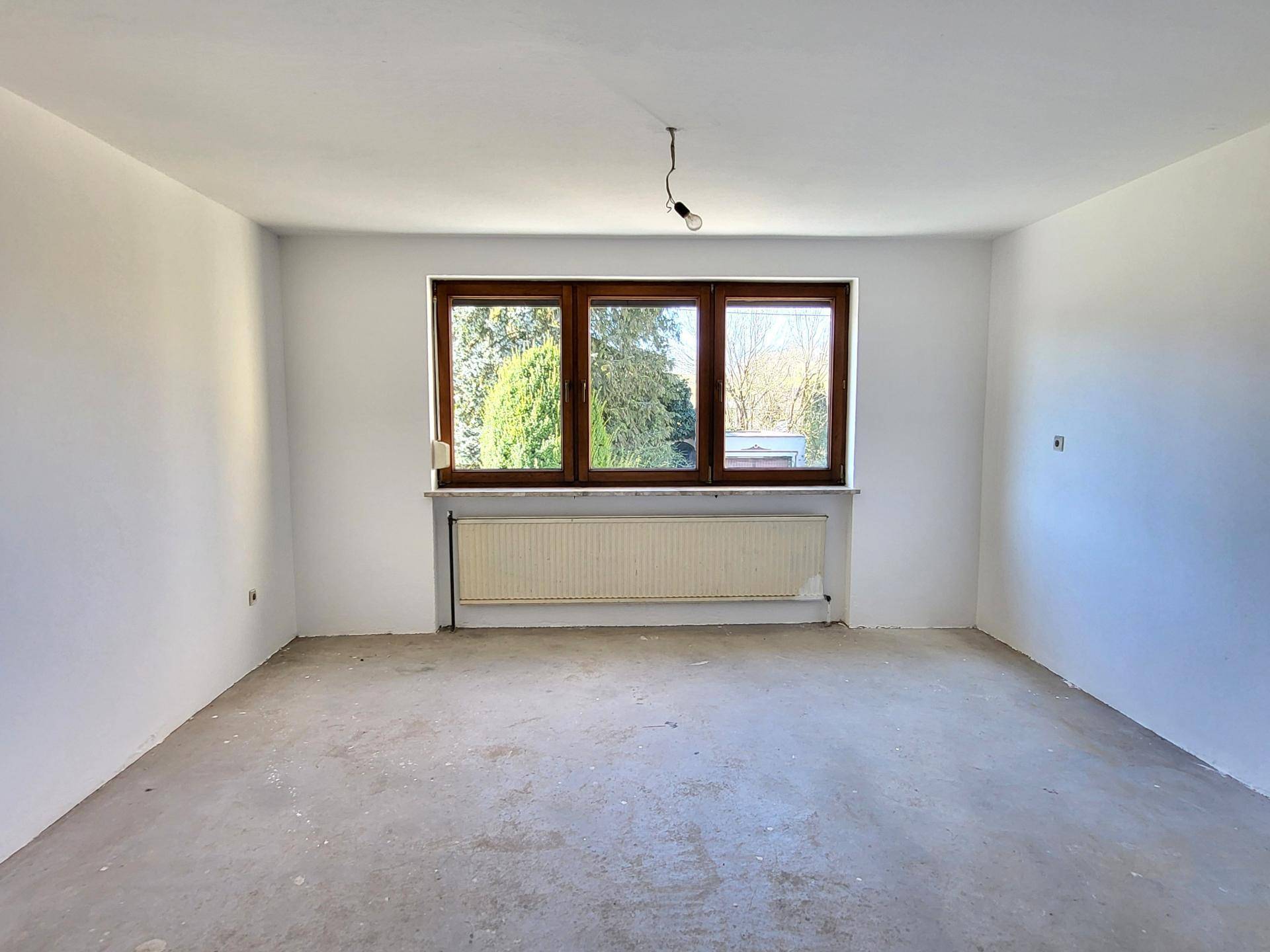Heller Raum mit drei Fenstern und Betonboden, ideal für individuelle Gestaltung.