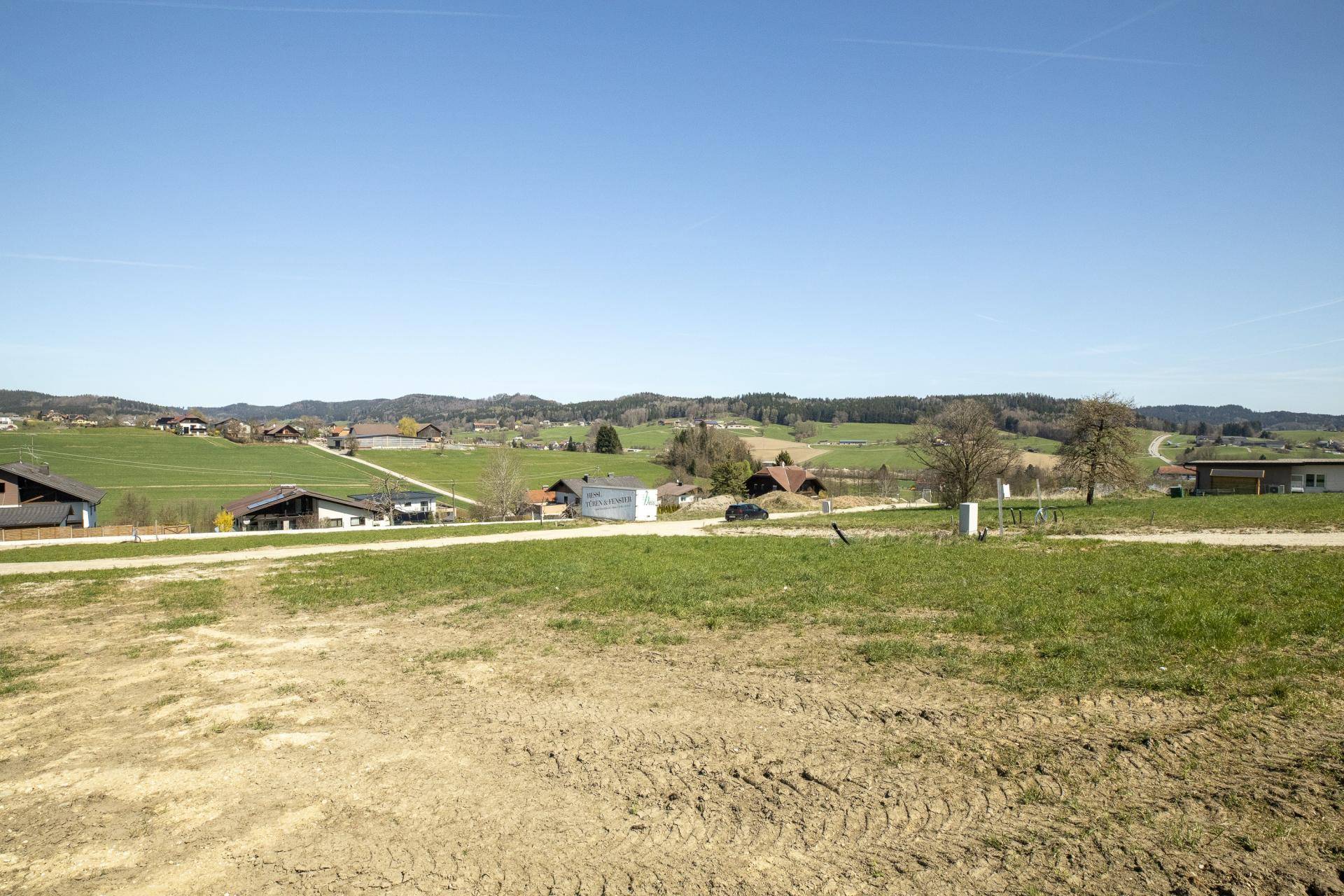Unbebautes Grundstück mit Blick auf die sanfte Hügellandschaft und verstreute Häuser in der Ferne.