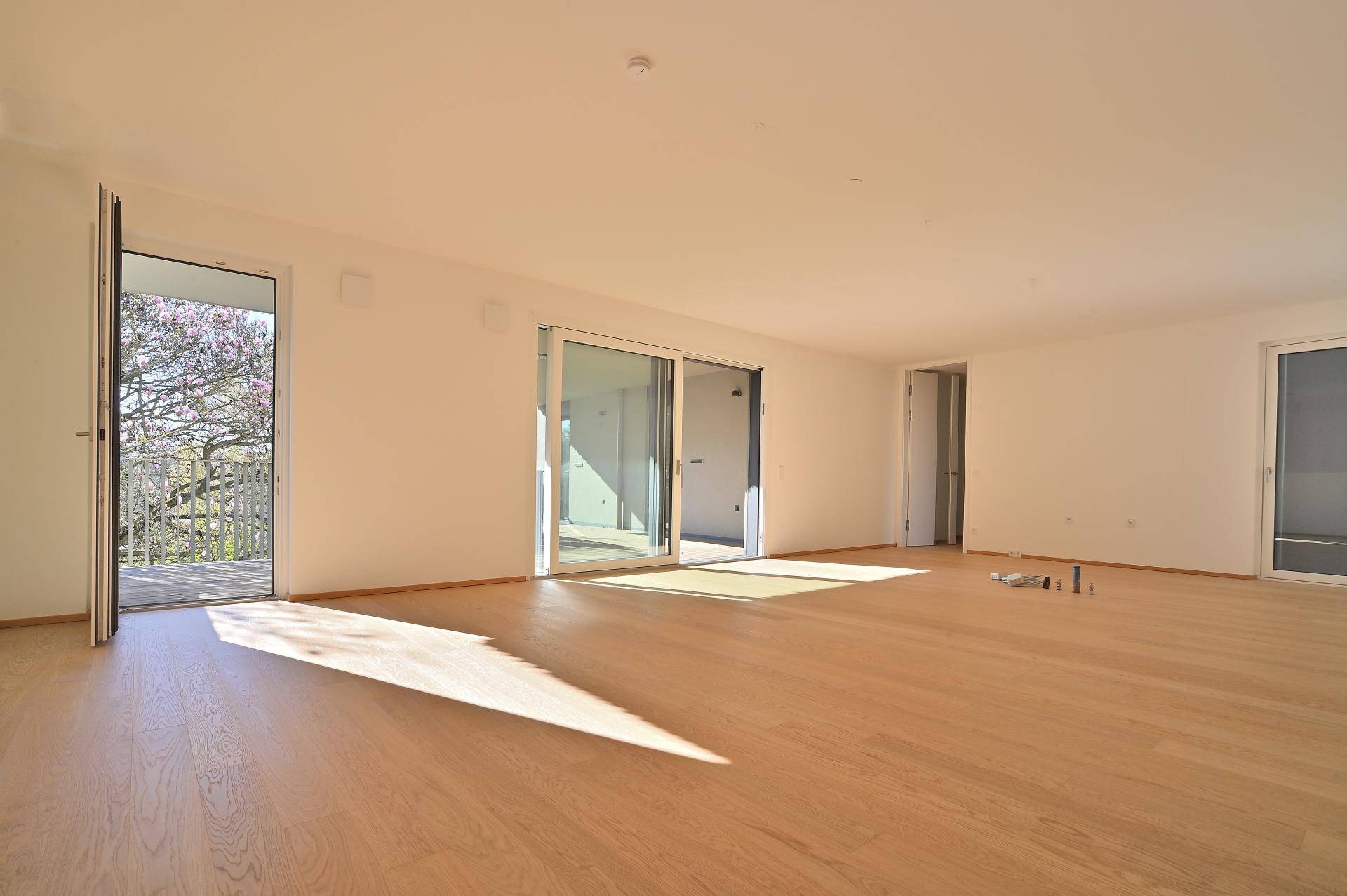 Geräumiges Wohnzimmer mit viel Tageslicht und Zugang zu mehreren Balkonen.