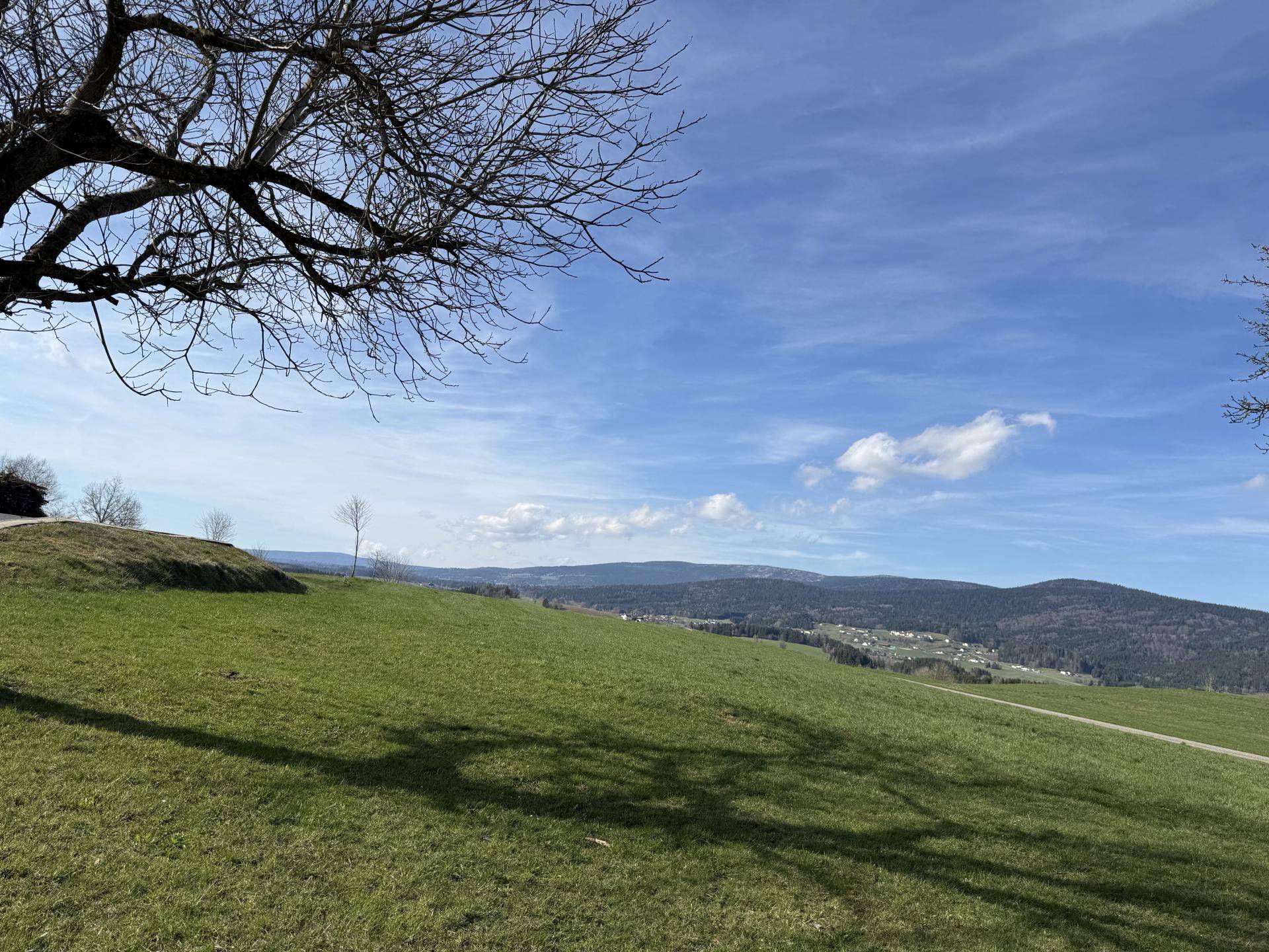 Weitläufige grüne Hügellandschaft unter blauem Himmel mit Fernblick.