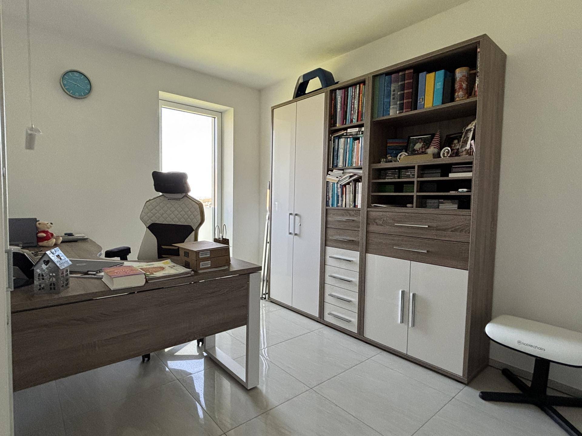 Funktionales Arbeitszimmer mit großem Schreibtisch und Bücherregal, bietet ausreichend Stauraum.