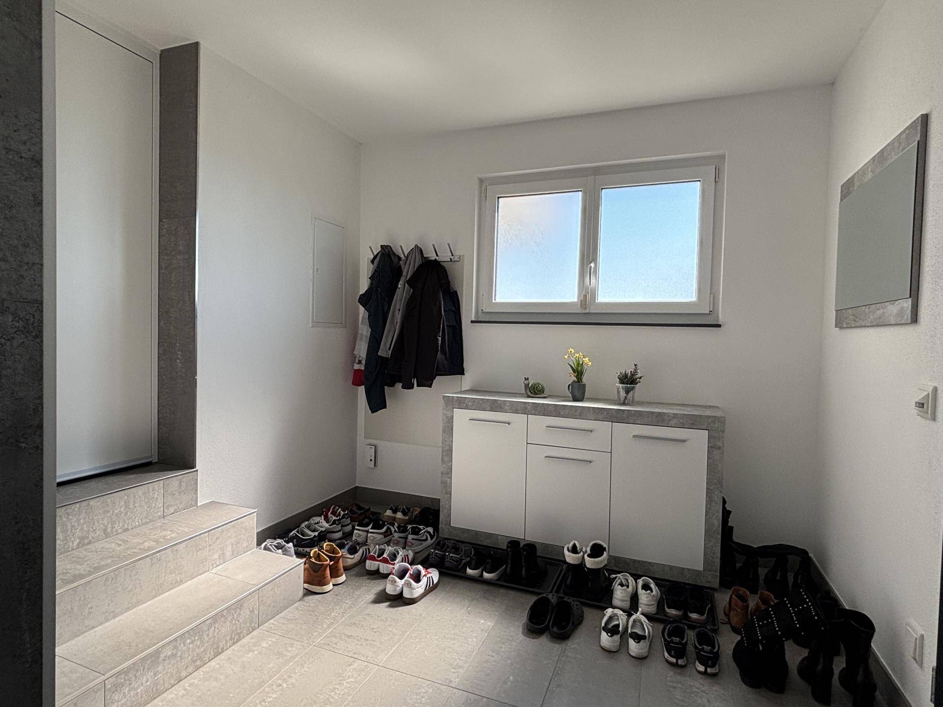 Heller Eingangsbereich mit praktischer Schuhablage, Garderobe und Treppenaufgang.