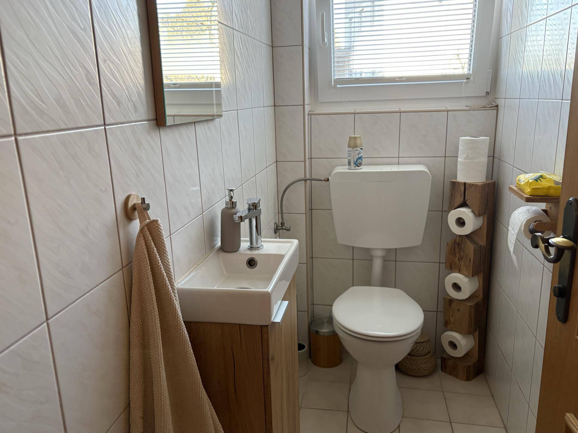 Kleines Gäste-WC mit Fliesenboden, Fenster und modernem Waschtisch.