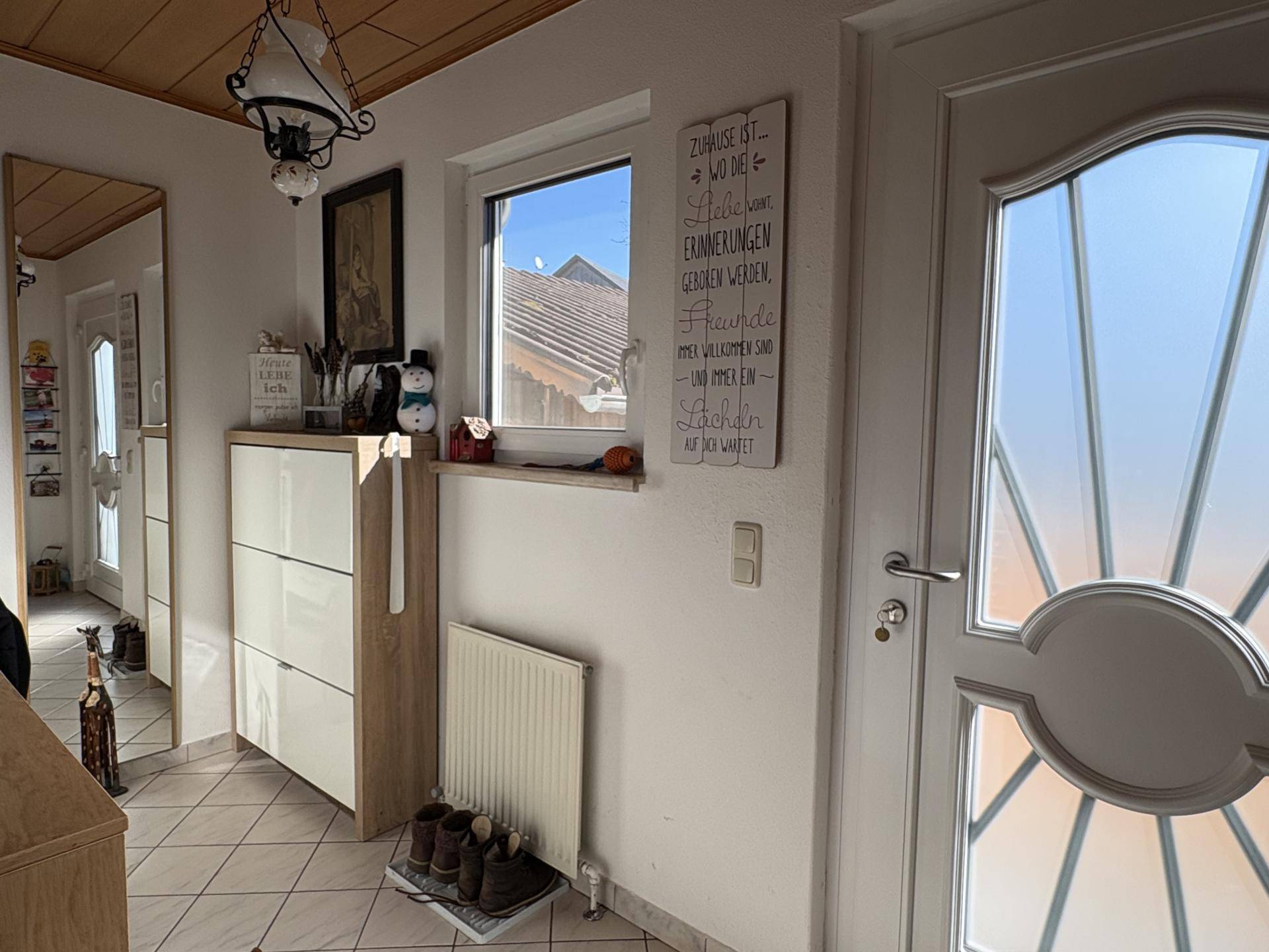 Heller Eingangsbereich mit Fliesenboden, Schuhschrank und Fenster.
