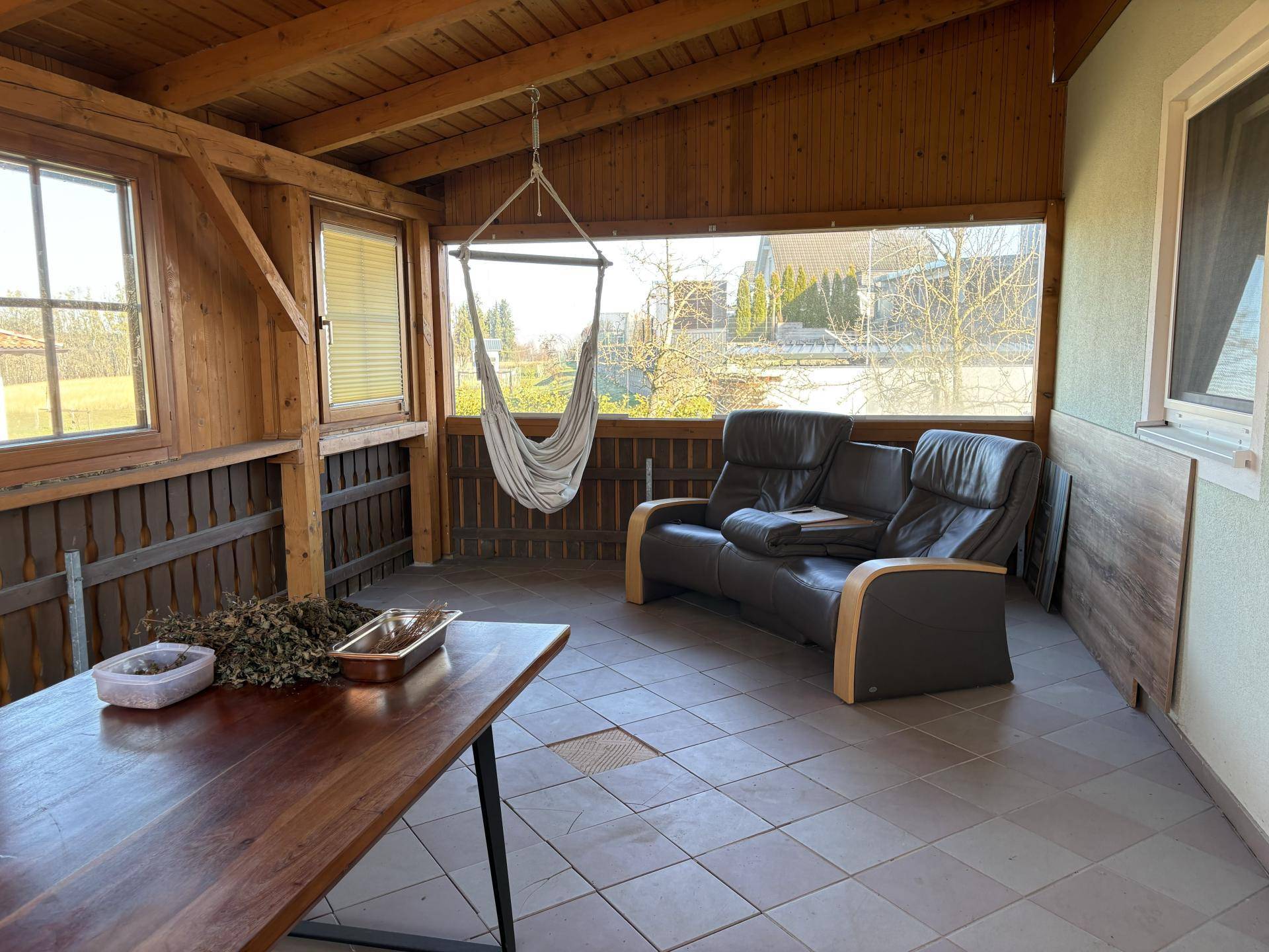 Überdachte Loggia mit Fliesenboden, bequemen Sesseln und Hängesessel.