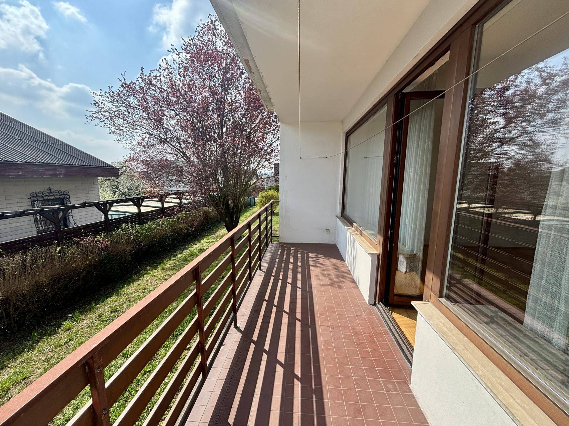 Langer Balkon mit Fliesenboden und Holzgeländer, ideal für entspannte Stunden im Freien.