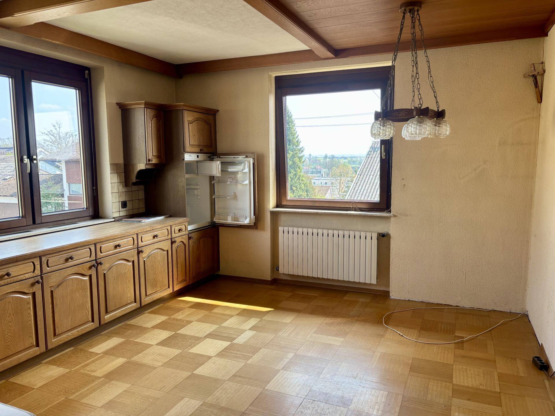 Küche mit traditionellen Holzschränken, Parkettboden und großem Fenster mit Weitblick.