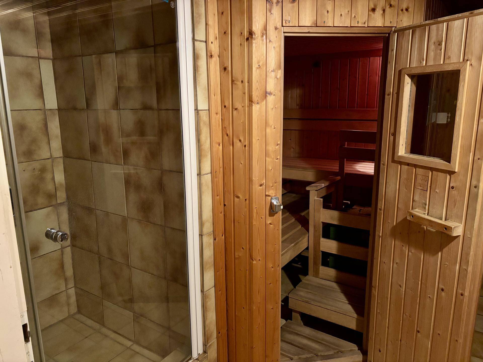 Private Sauna mit Holzausstattung und angrenzender Duschkabine für Wellnessmomente.