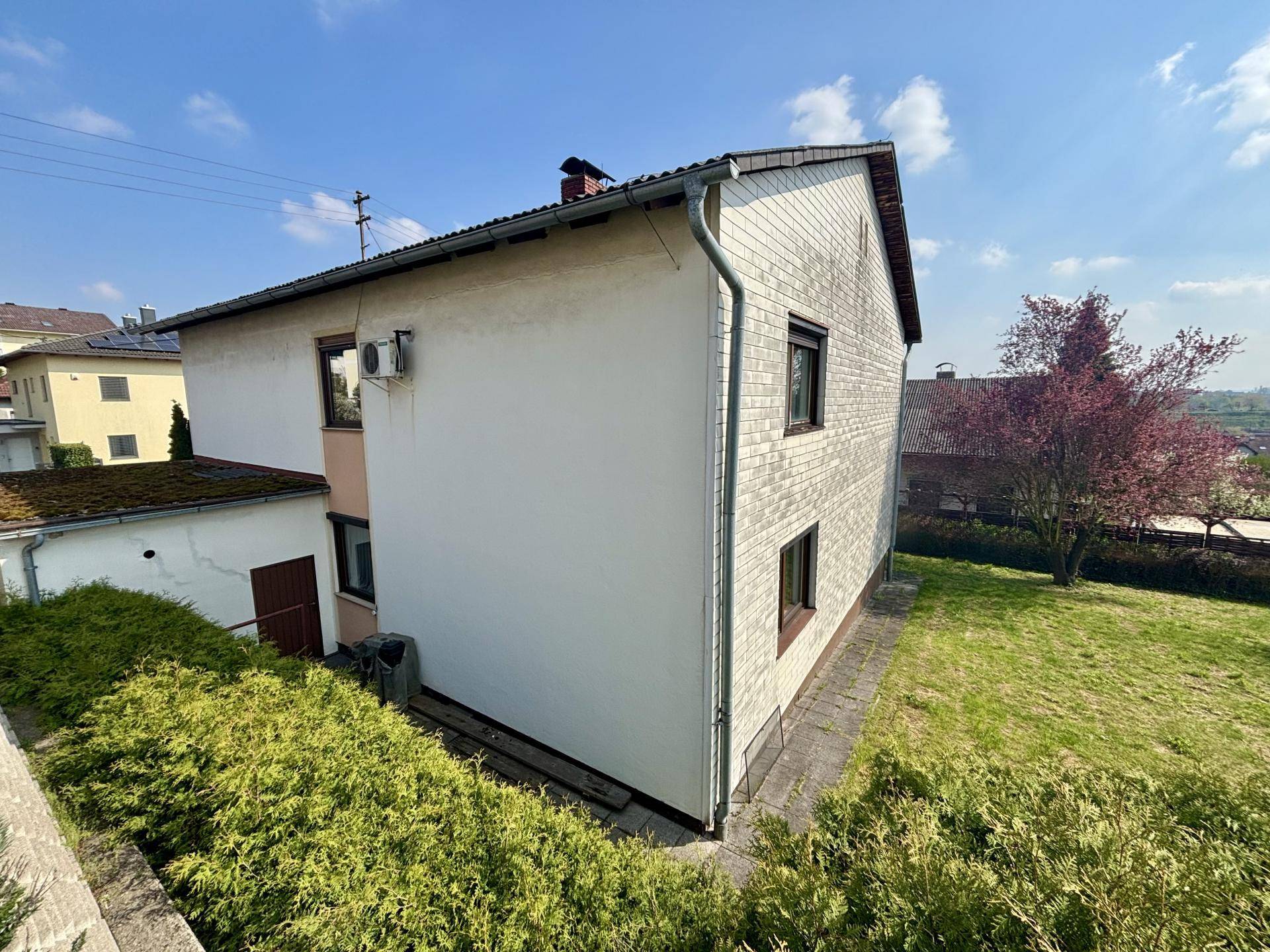 Rückseite des Hauses mit großem Gartenbereich und viel Grün, ideal für Erholung.