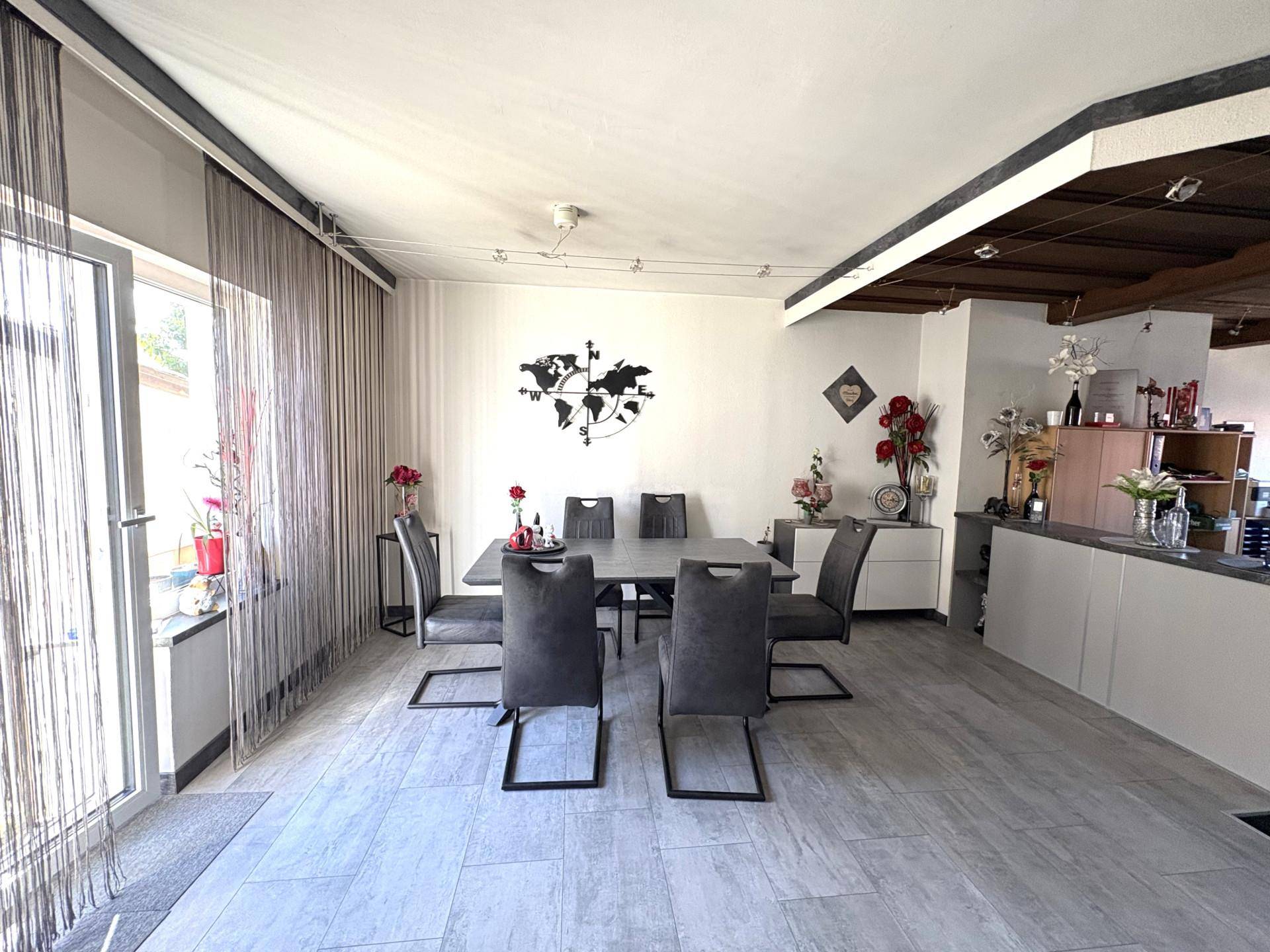 Moderner Essbereich mit großem Tisch, bequemen Stühlen und Zugang zur Terrasse.