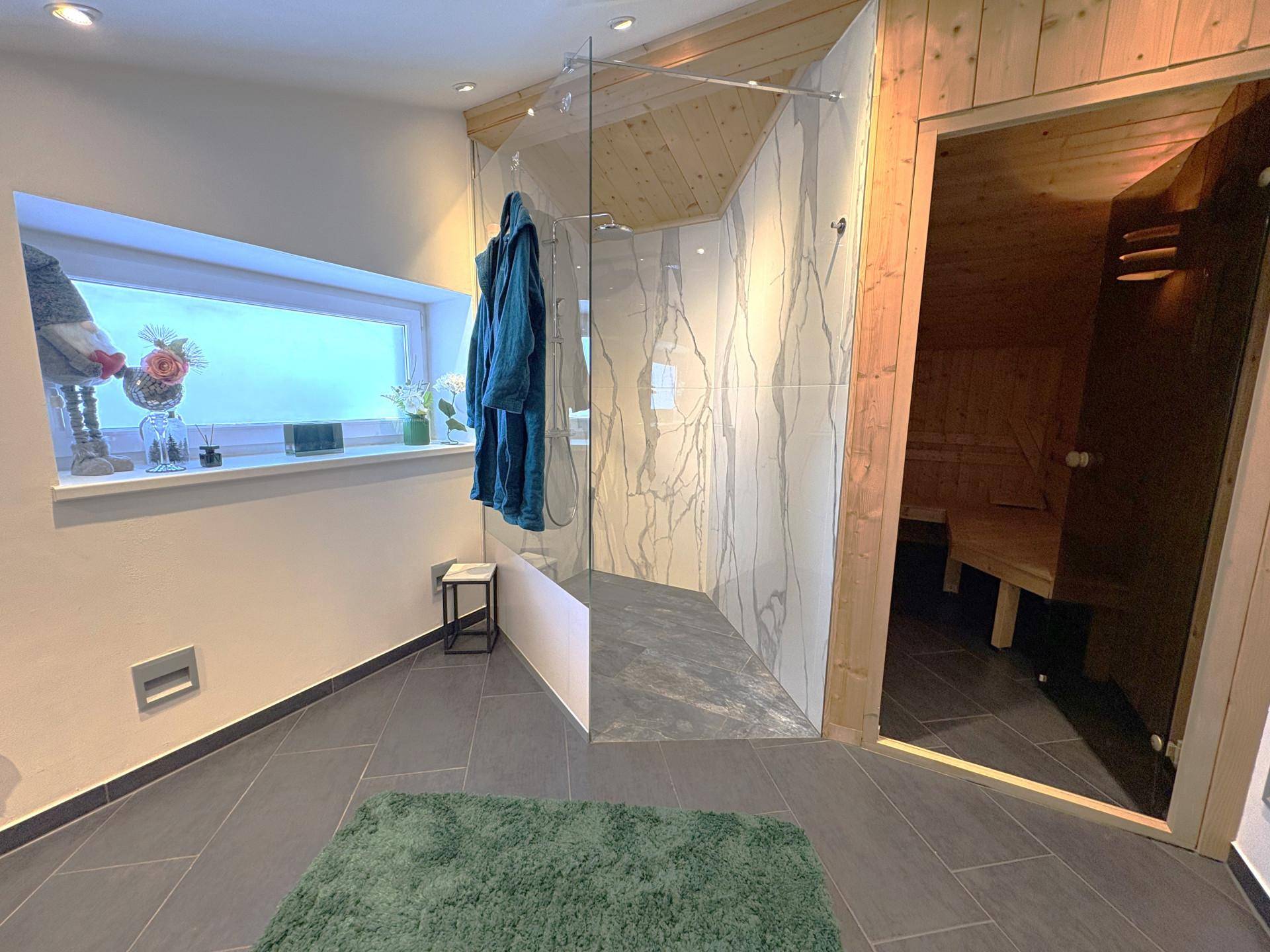 Modernes Badezimmer mit großer begehbarer Dusche, Sauna und Fenster.