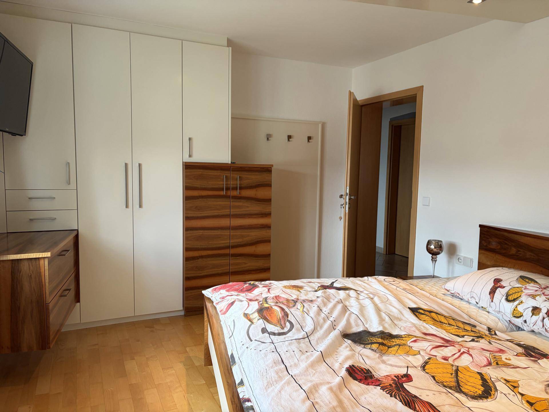 Schlafzimmer mit weißem Einbauschrank, Holzakzenten und Blick auf den Flur.