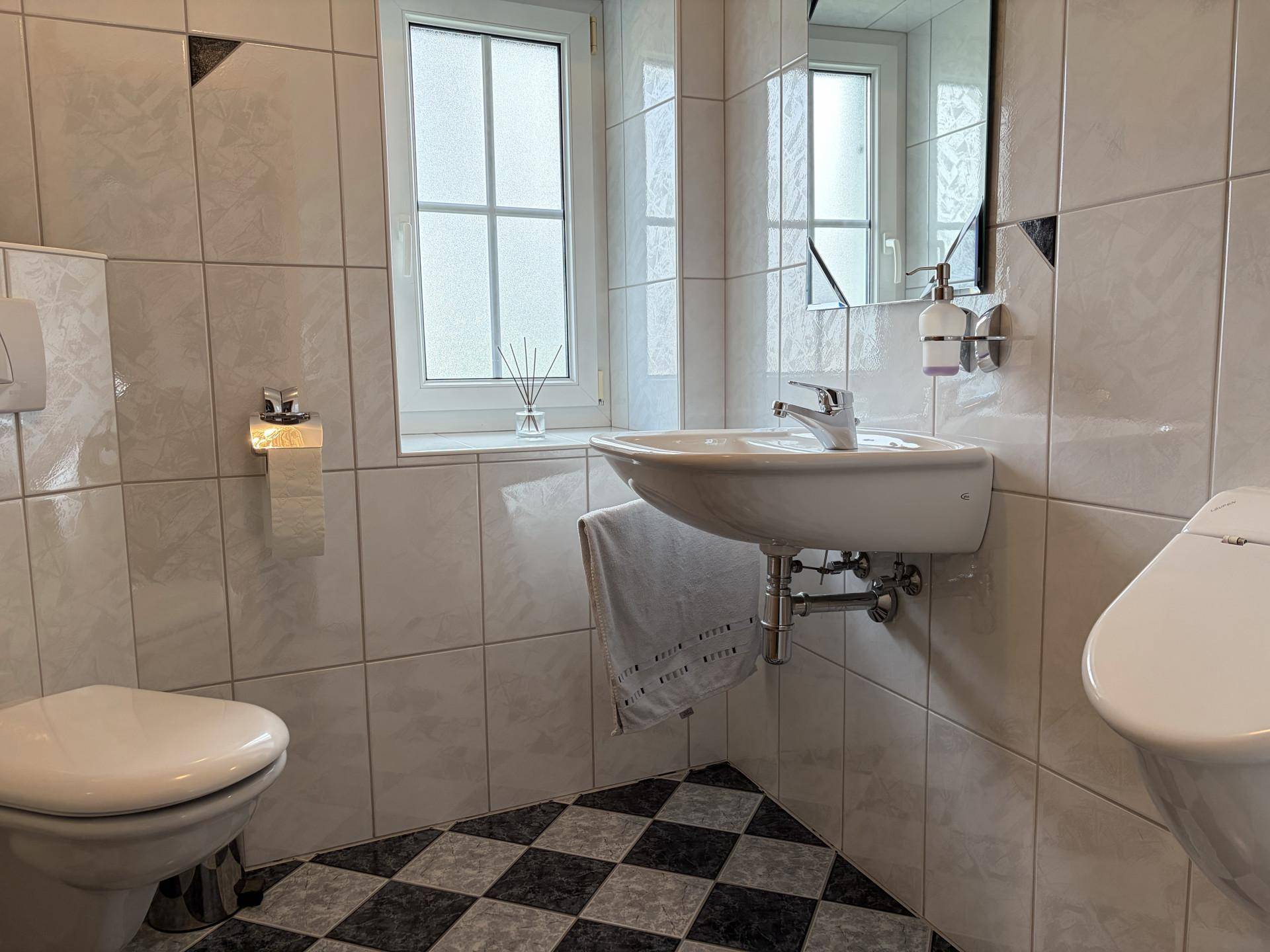 Kleines Gäste-WC mit Schachbrettmuster-Fliesenboden und Fenster.