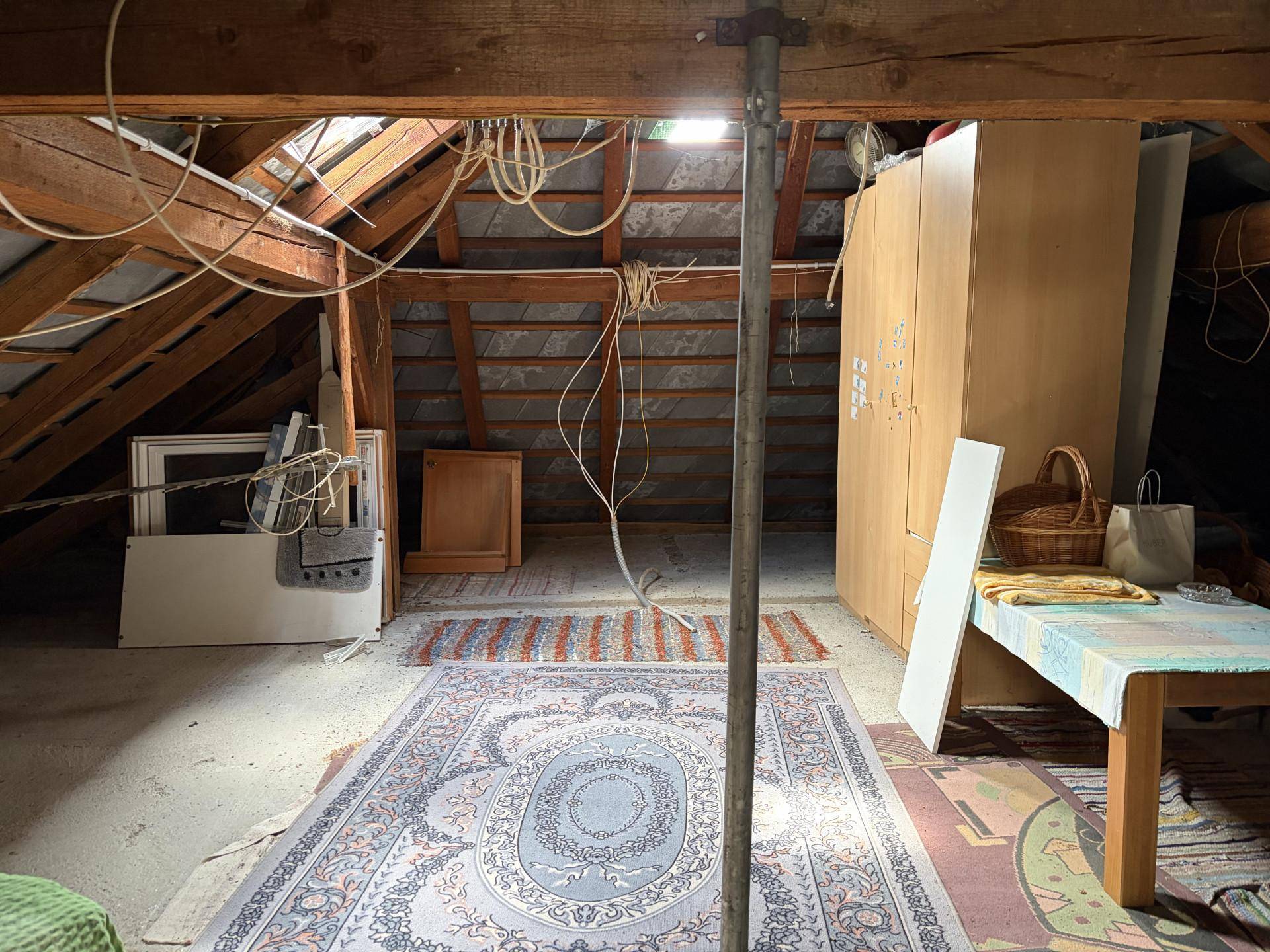 Unausgebauter Dachboden mit sichtbaren Holzbalken und Lagerfläche.