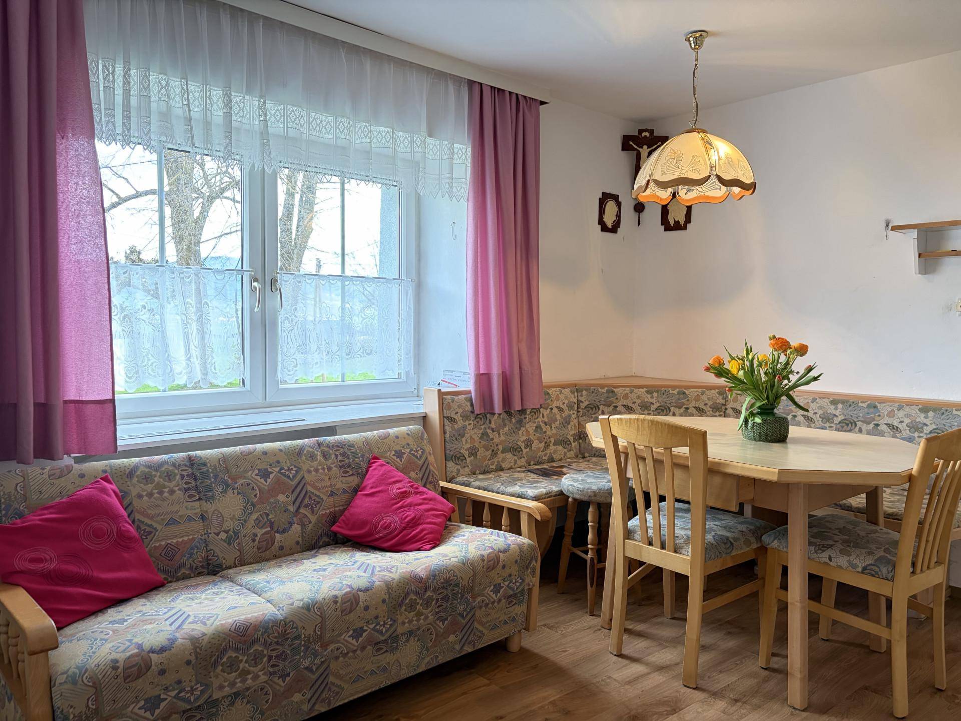 Heller Wohn- und Essbereich mit Sofa, Esstisch und Blick auf die Umgebung.