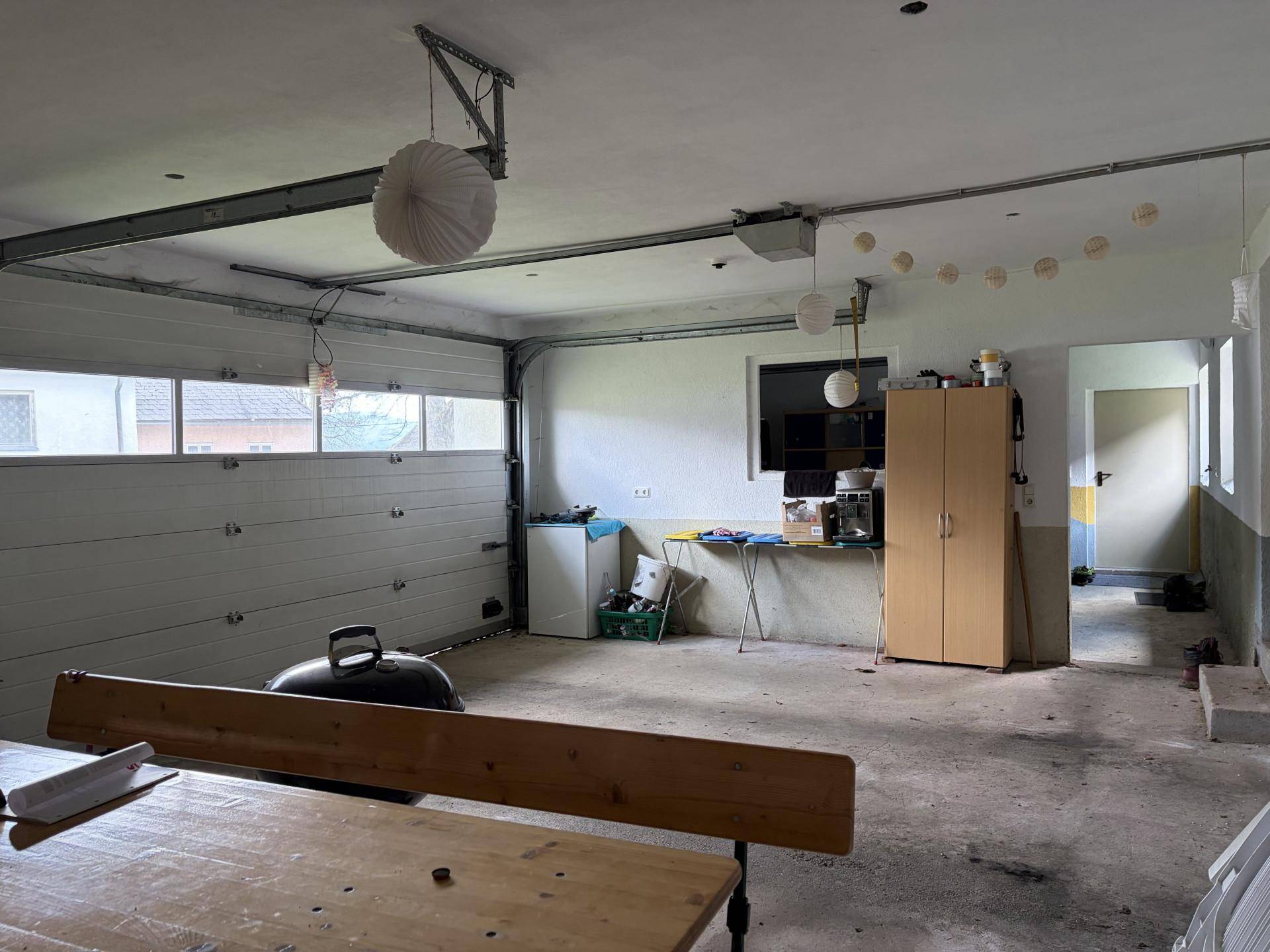 Geräumige Garage mit Rolltor, Werkbank und ausreichend Platz.
