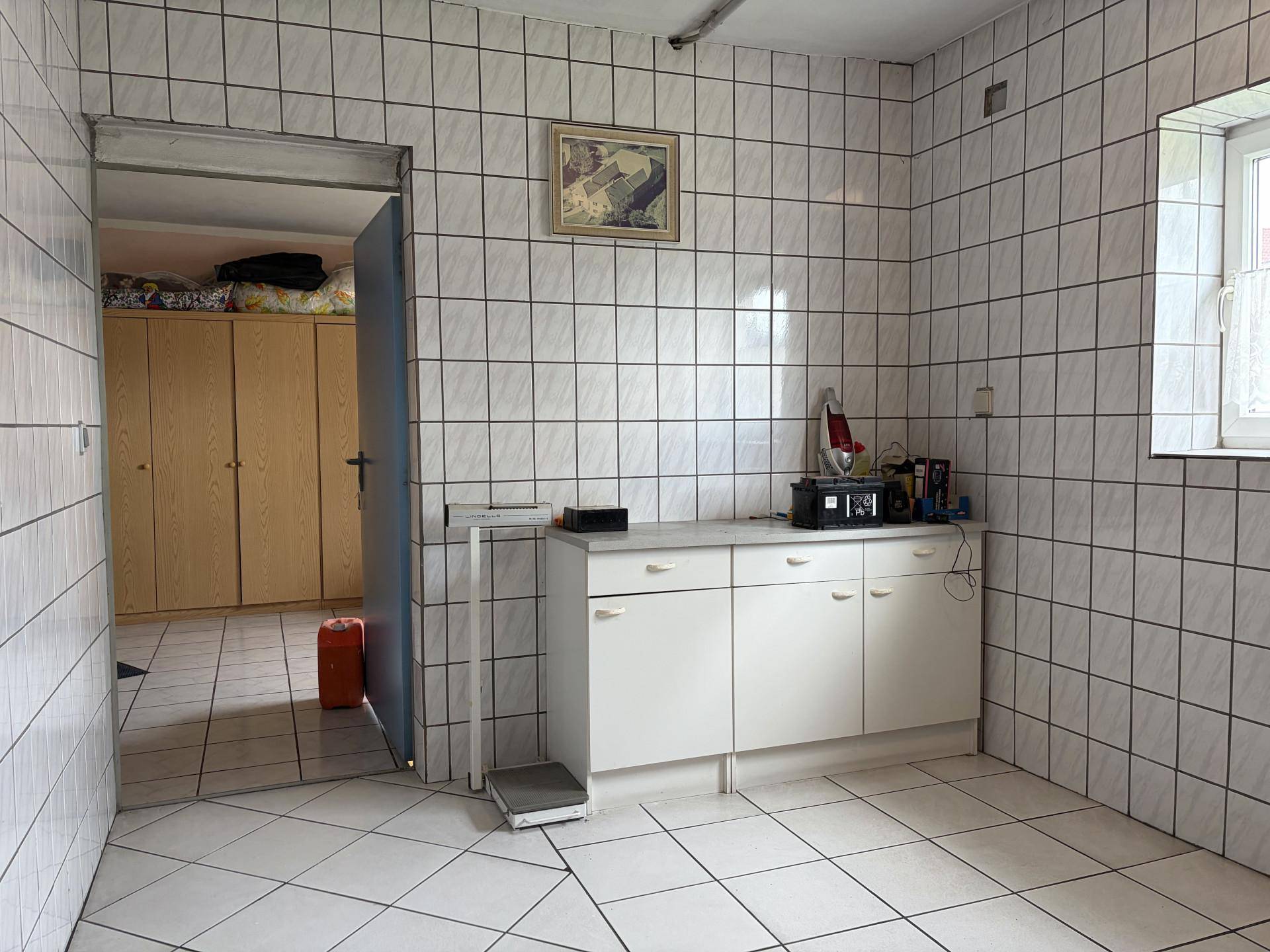 Gefliester Lagerraum im Keller mit Schränken und Zugang zu weiteren Räumen.