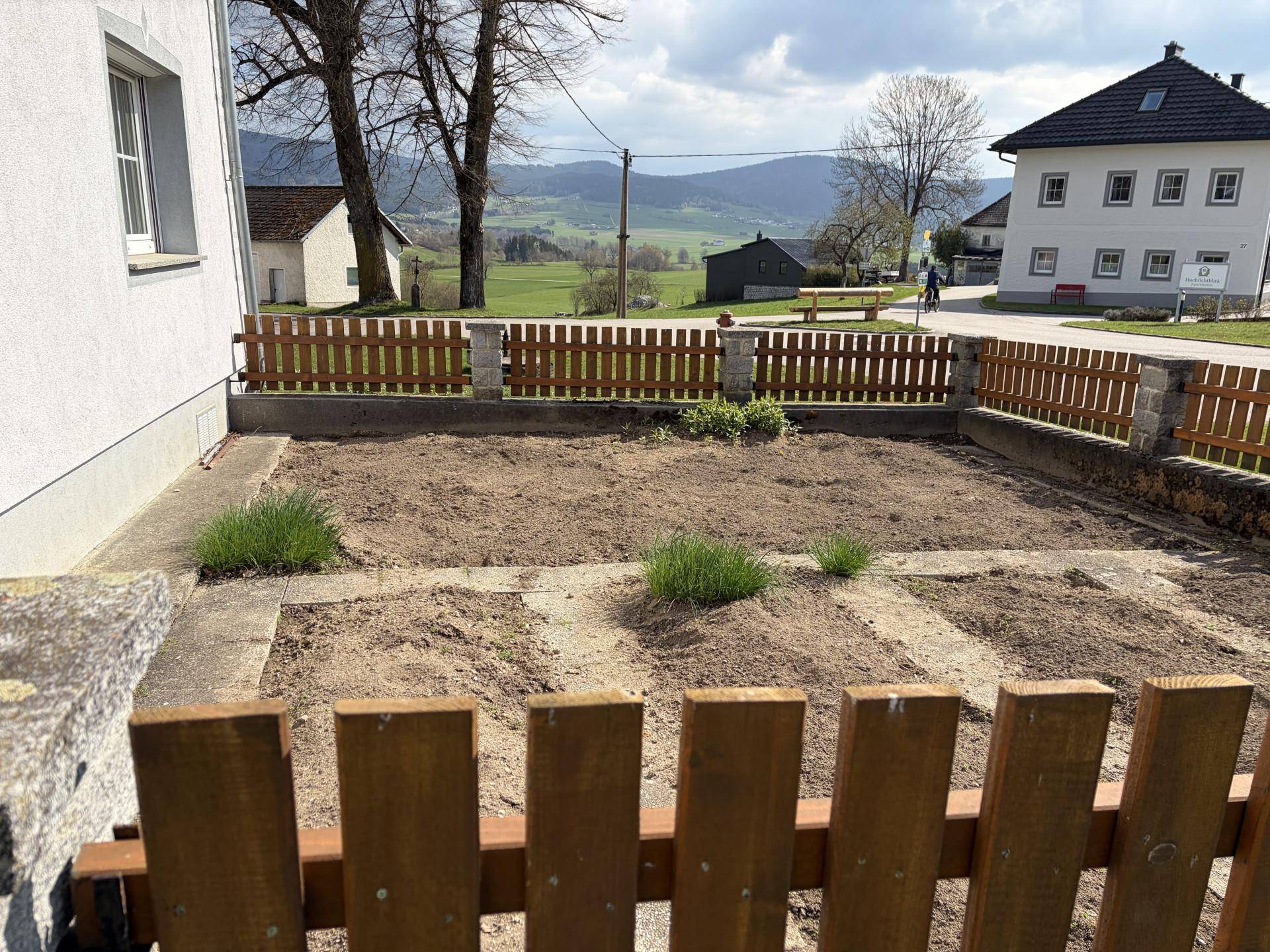 Kleiner Vorgarten mit Holzzaun und Blick auf die umliegende Landschaft.