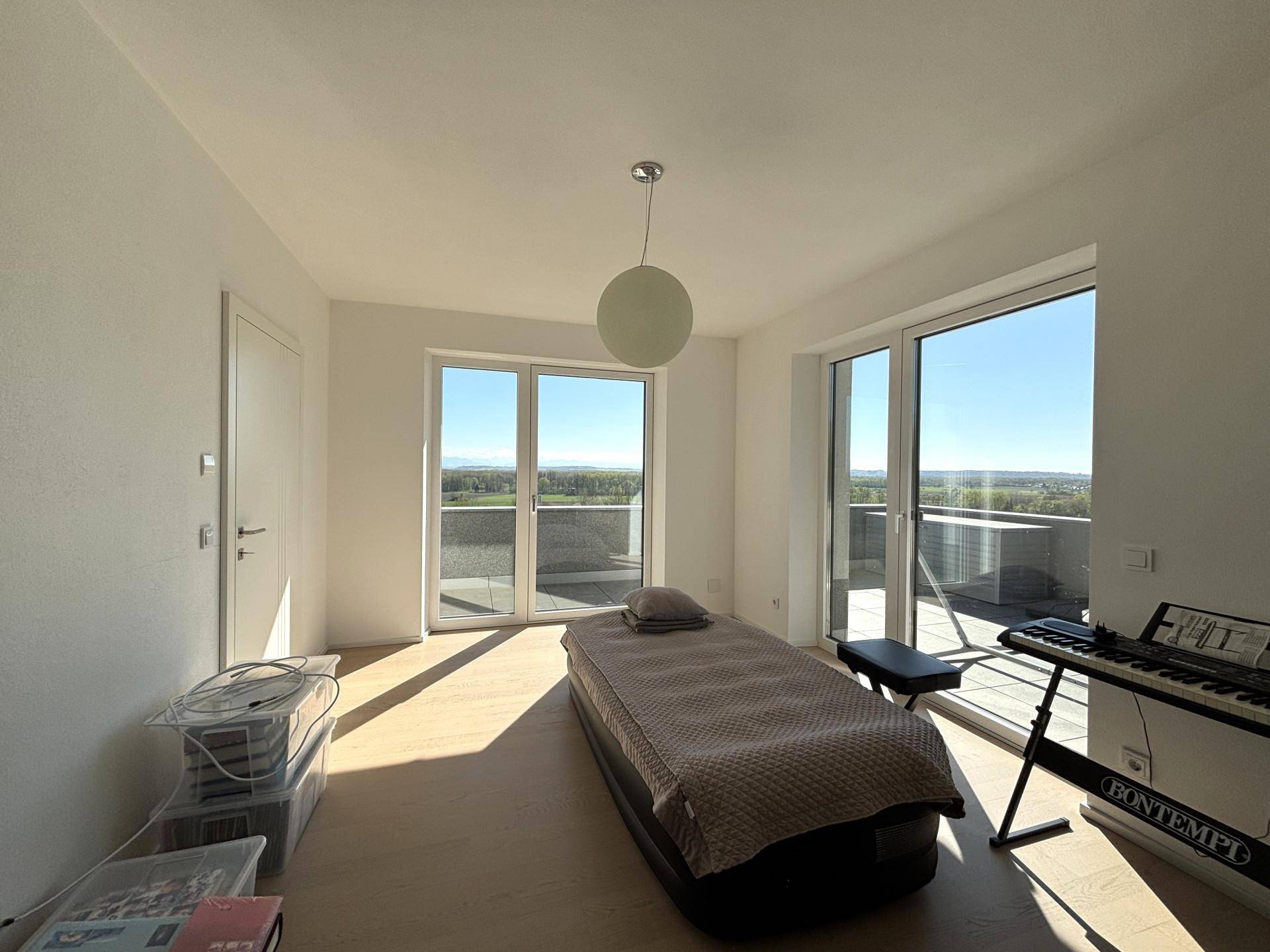Lichtdurchflutetes Schlafzimmer mit großen Fenstern und Terrassenzugang, bietet weite Aussicht.