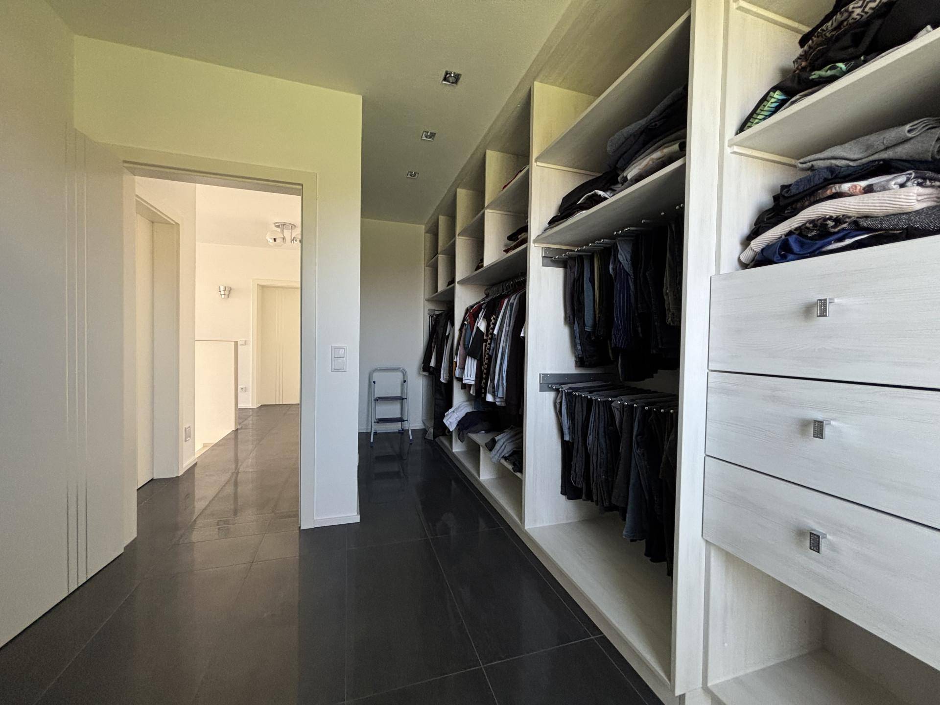 Geräumiger begehbarer Kleiderschrank mit vielen Regalen und Hängemöglichkeiten für Kleidung.